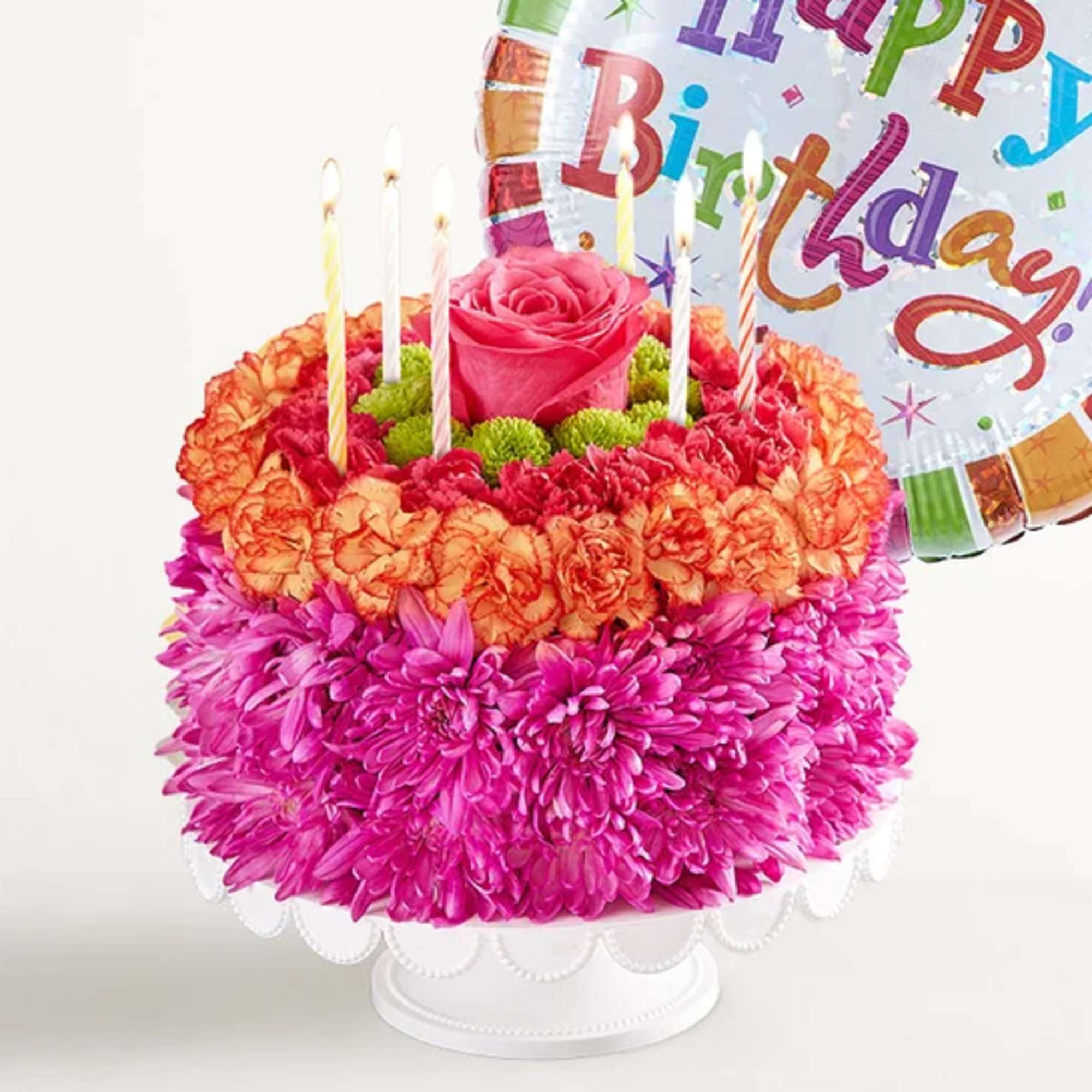 Birthday cake made of pink and orange flowers with candles and a balloon
