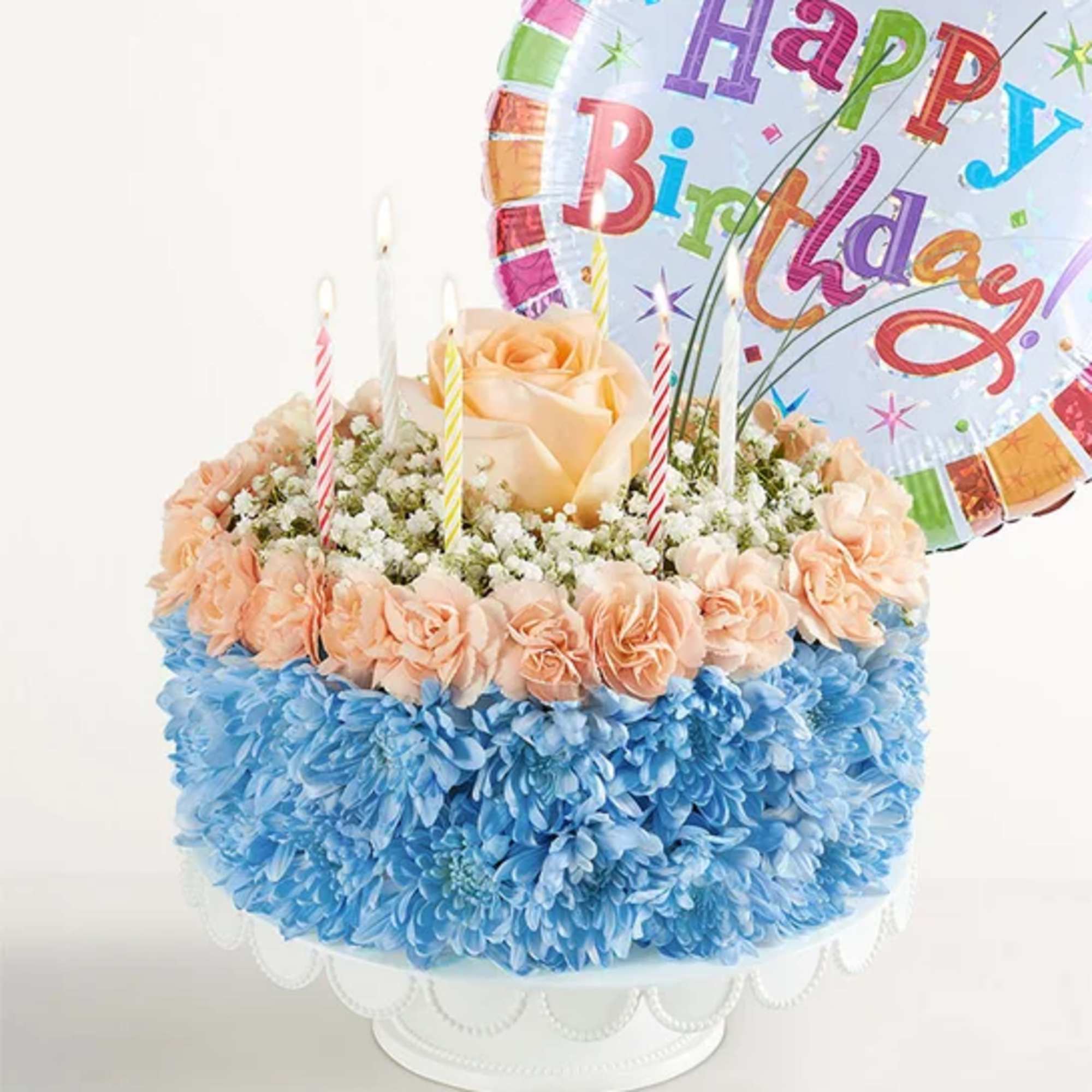 Birthday cake-shaped flower arrangement with candles and a balloon