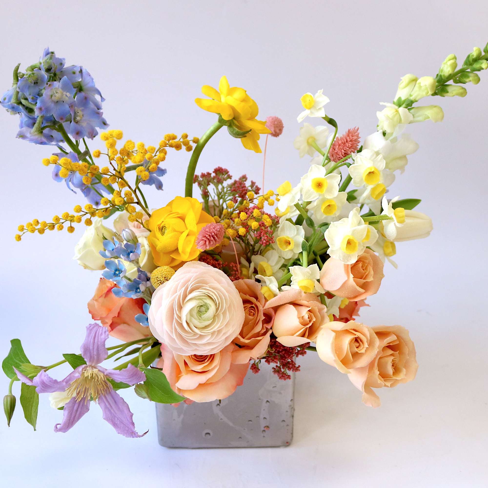 Mixed bouquet in a gray square vase with pastel flowers