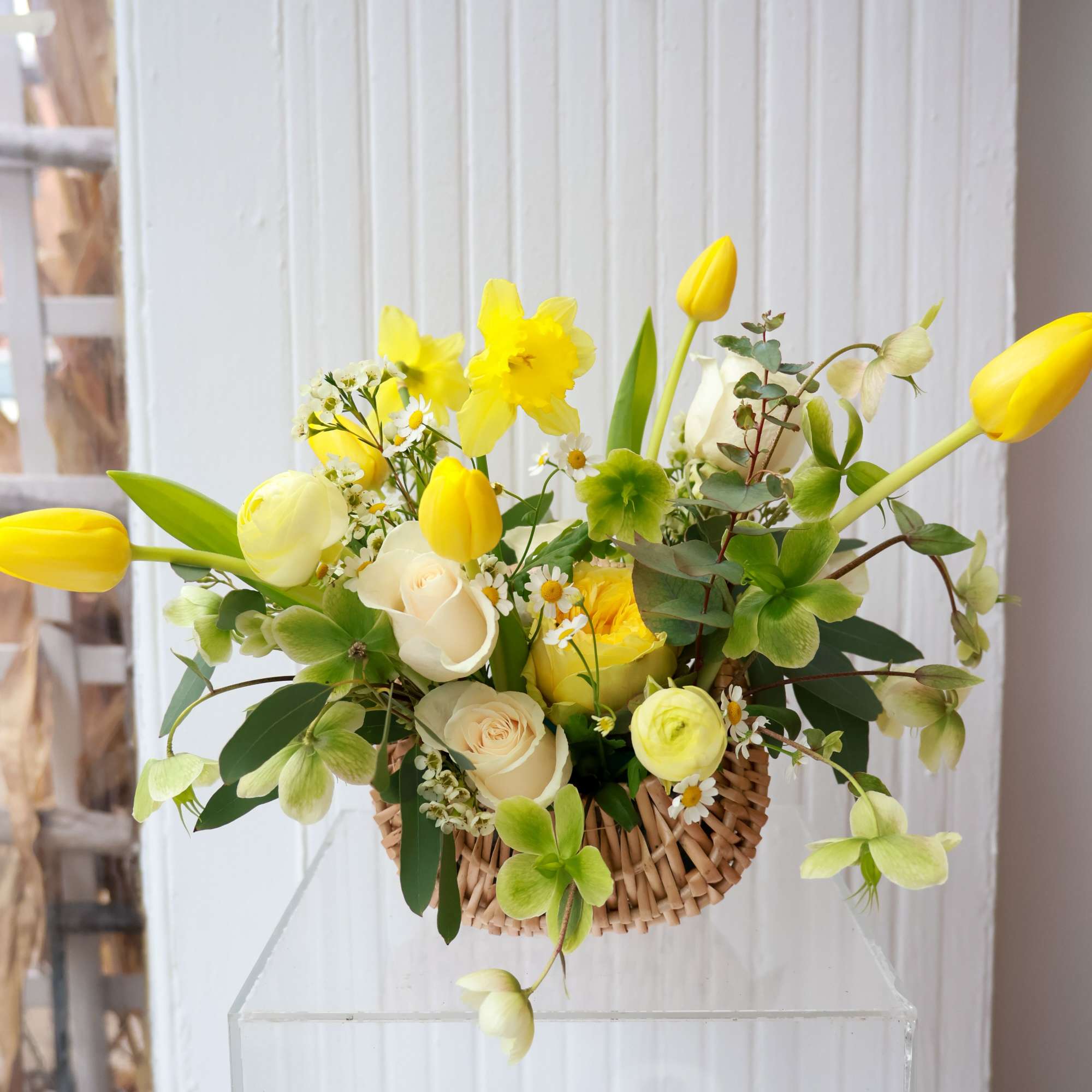 Yellow tulips and white roses in a woven basket arrangement
