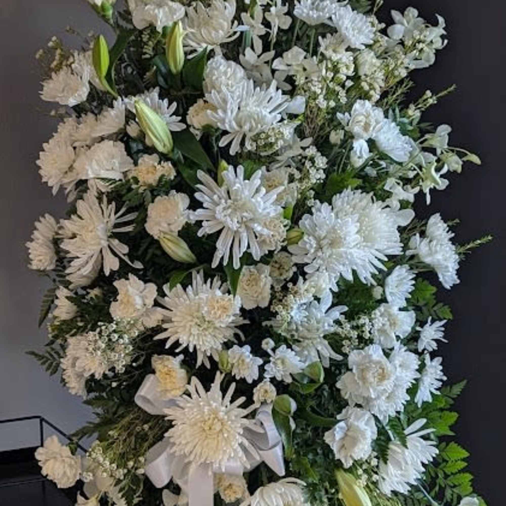 Large white floral standing spray with lilies and daisies on an easel