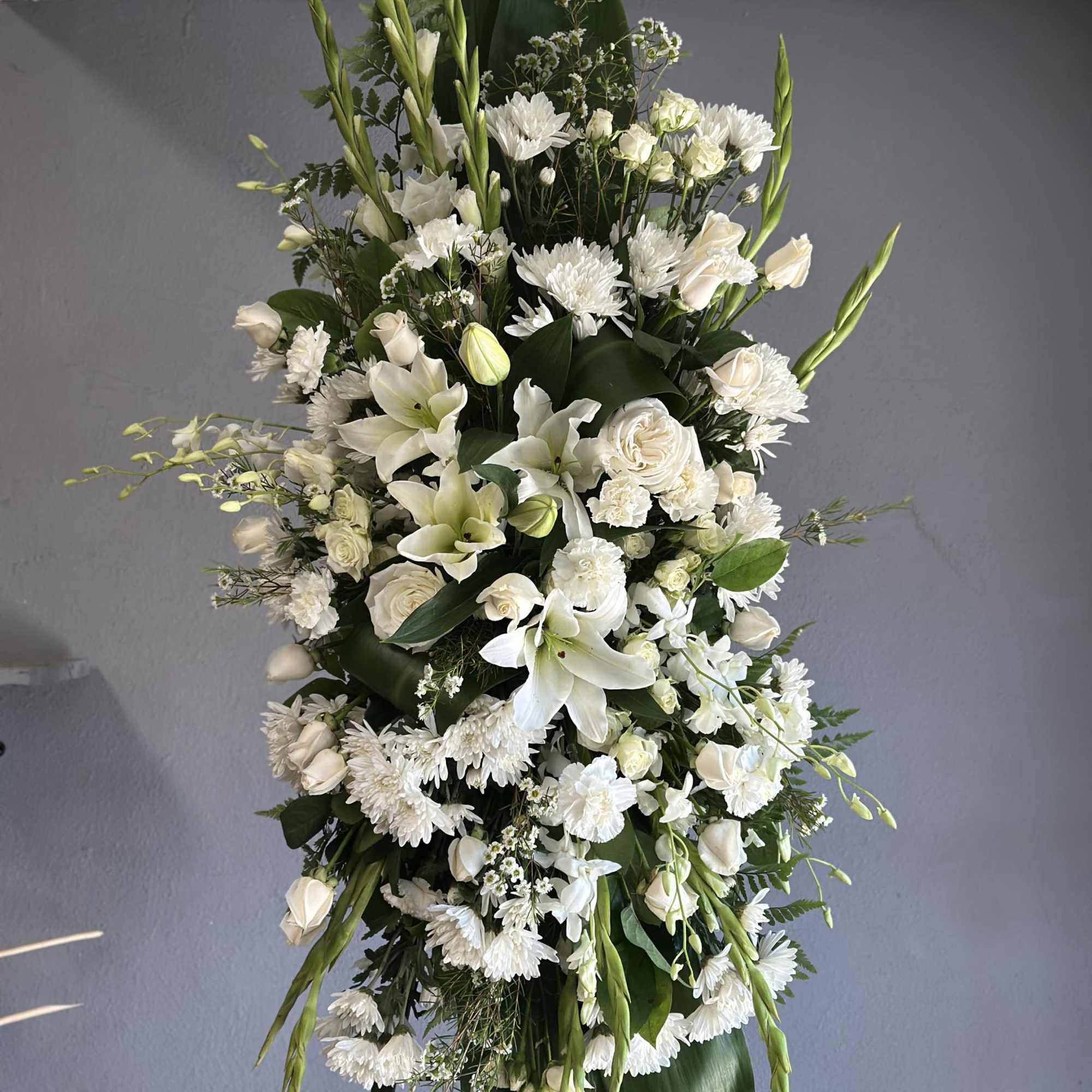 Tall white floral standing spray with lilies, roses, and chrysanthemums