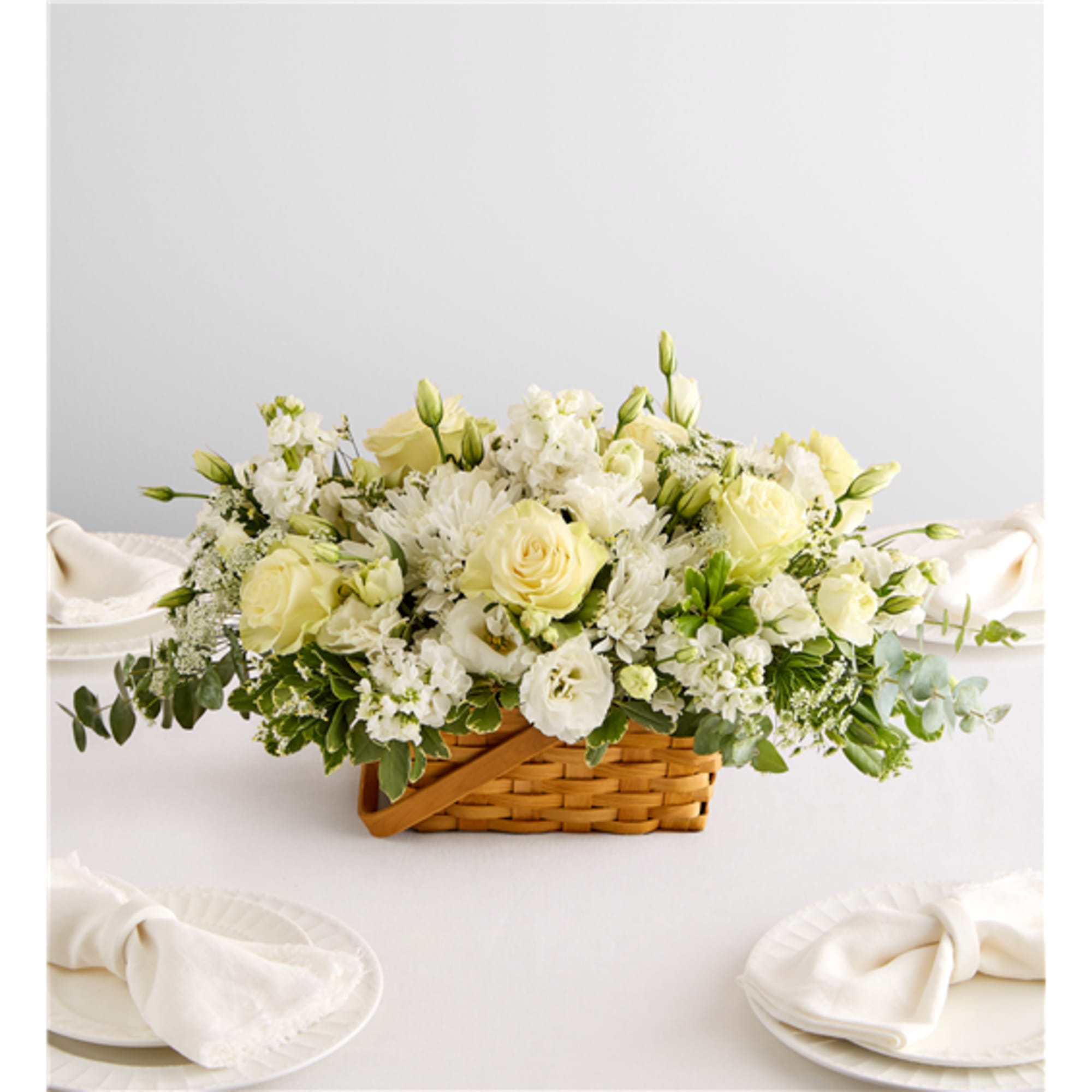 White and pale yellow floral centerpiece in a woven basket