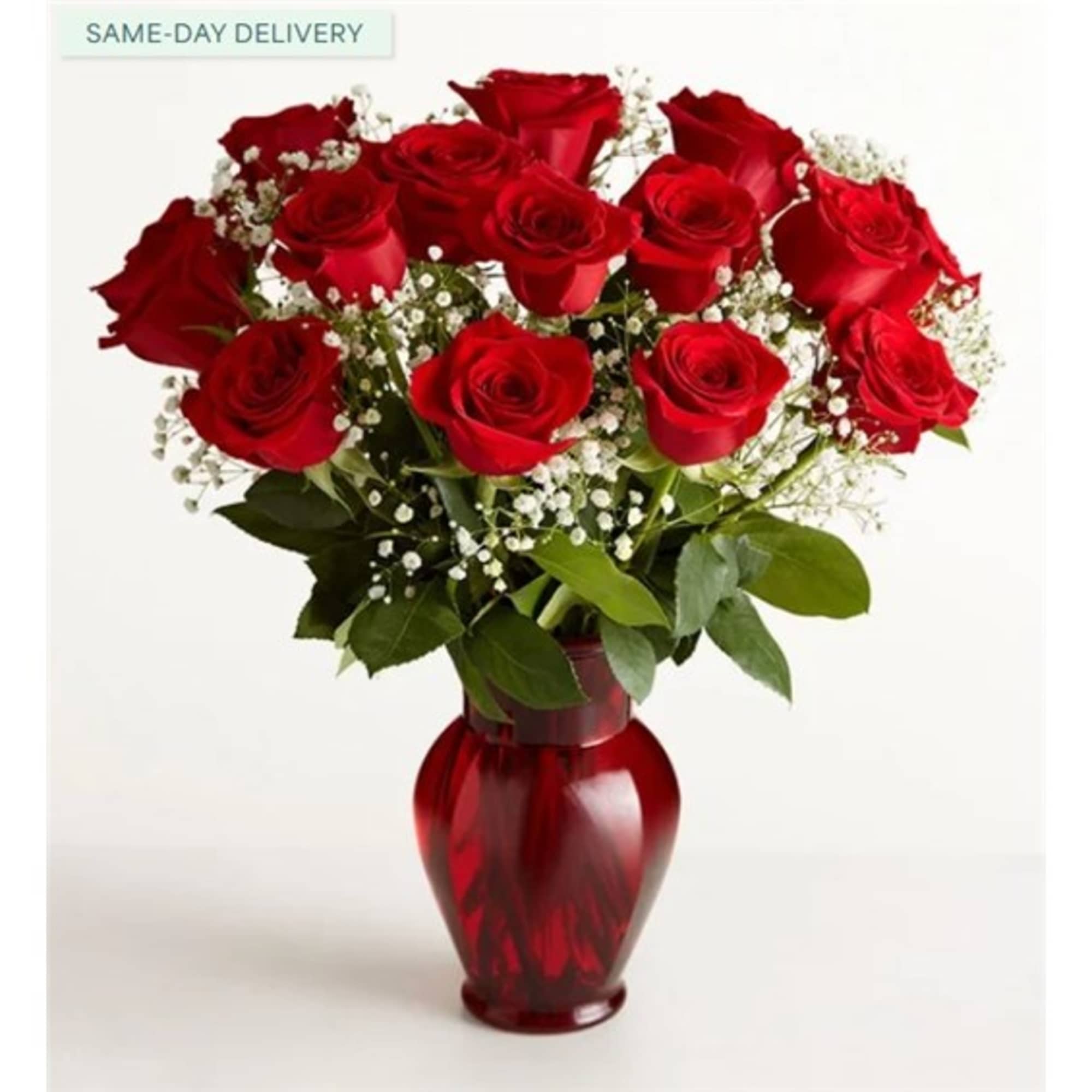 Red roses arranged in a red glass vase with white baby's breath