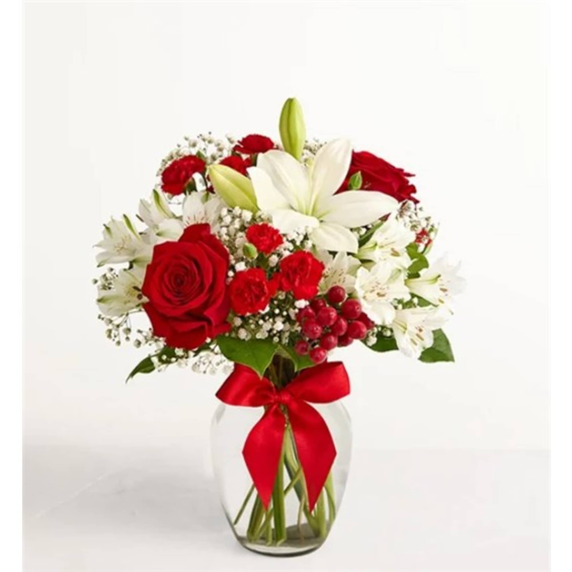Red roses and white lilies in a clear glass vase with a red ribbon