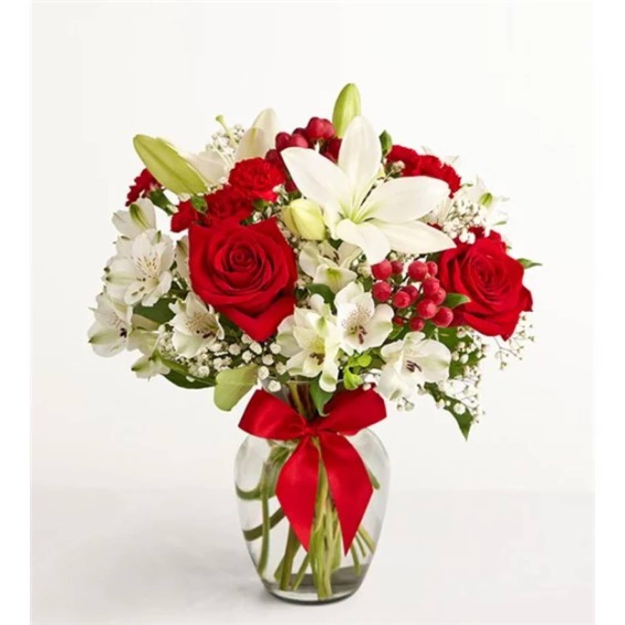 Bouquet of red roses and white lilies in a glass vase with a red ribbon