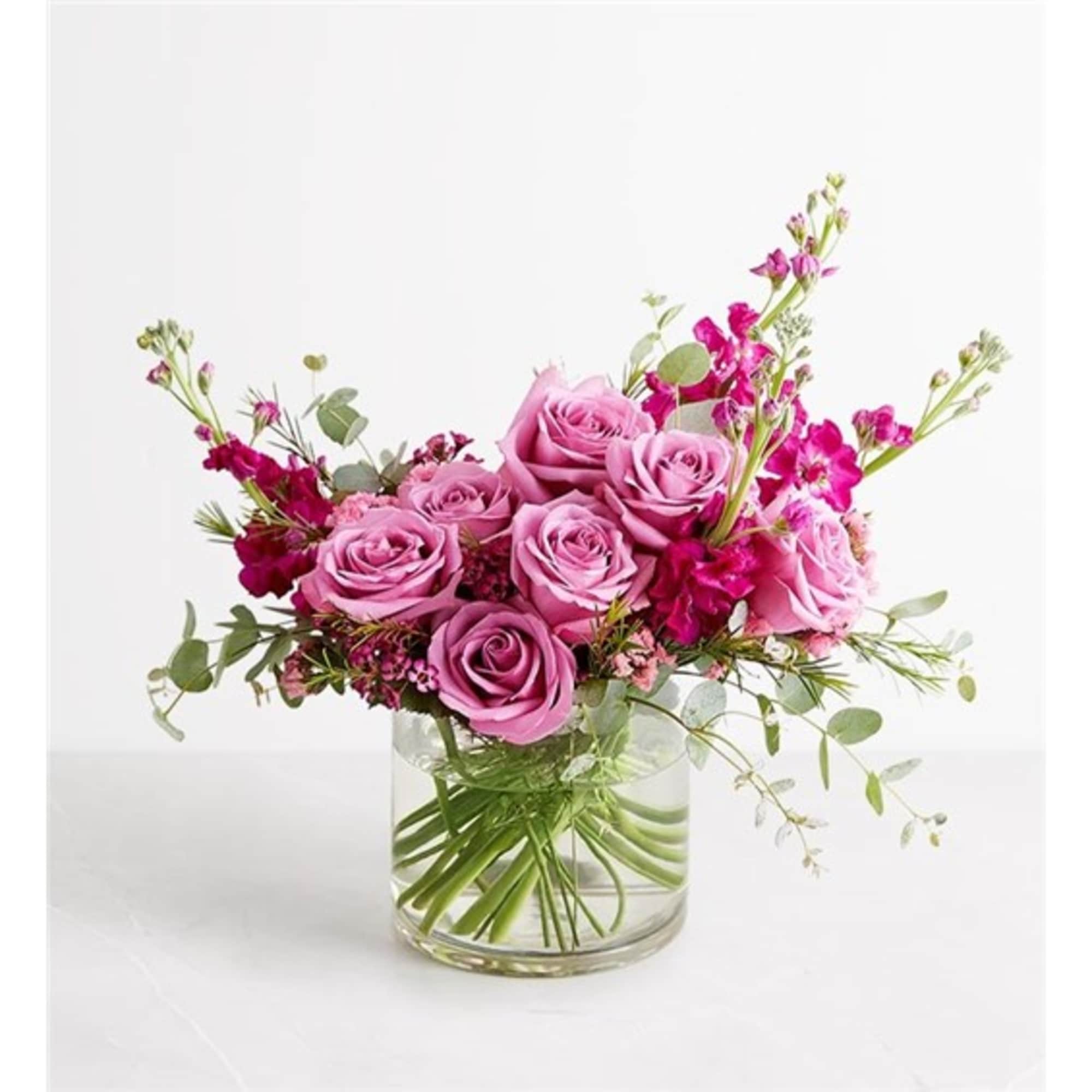 Pink roses in a clear glass vase with magenta accent flowers