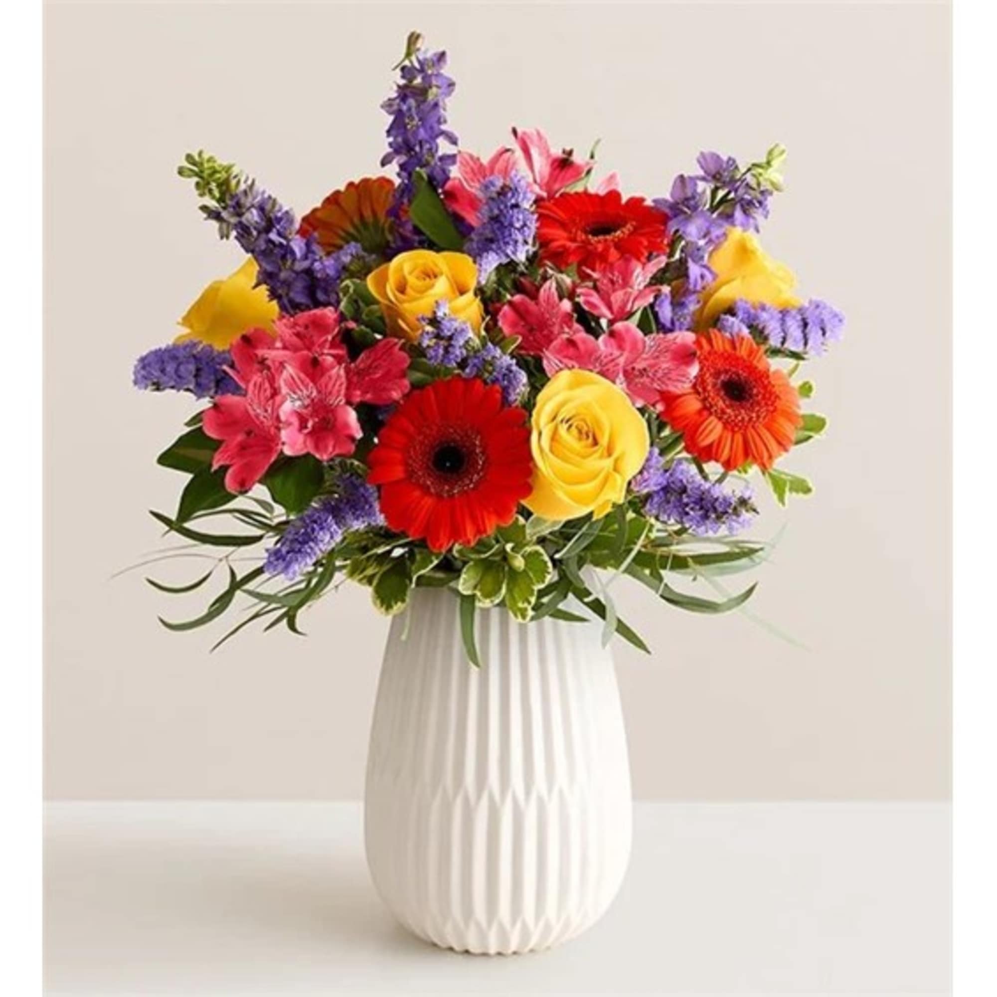 Colorful mixed bouquet in a white vase with roses and gerbera daisies