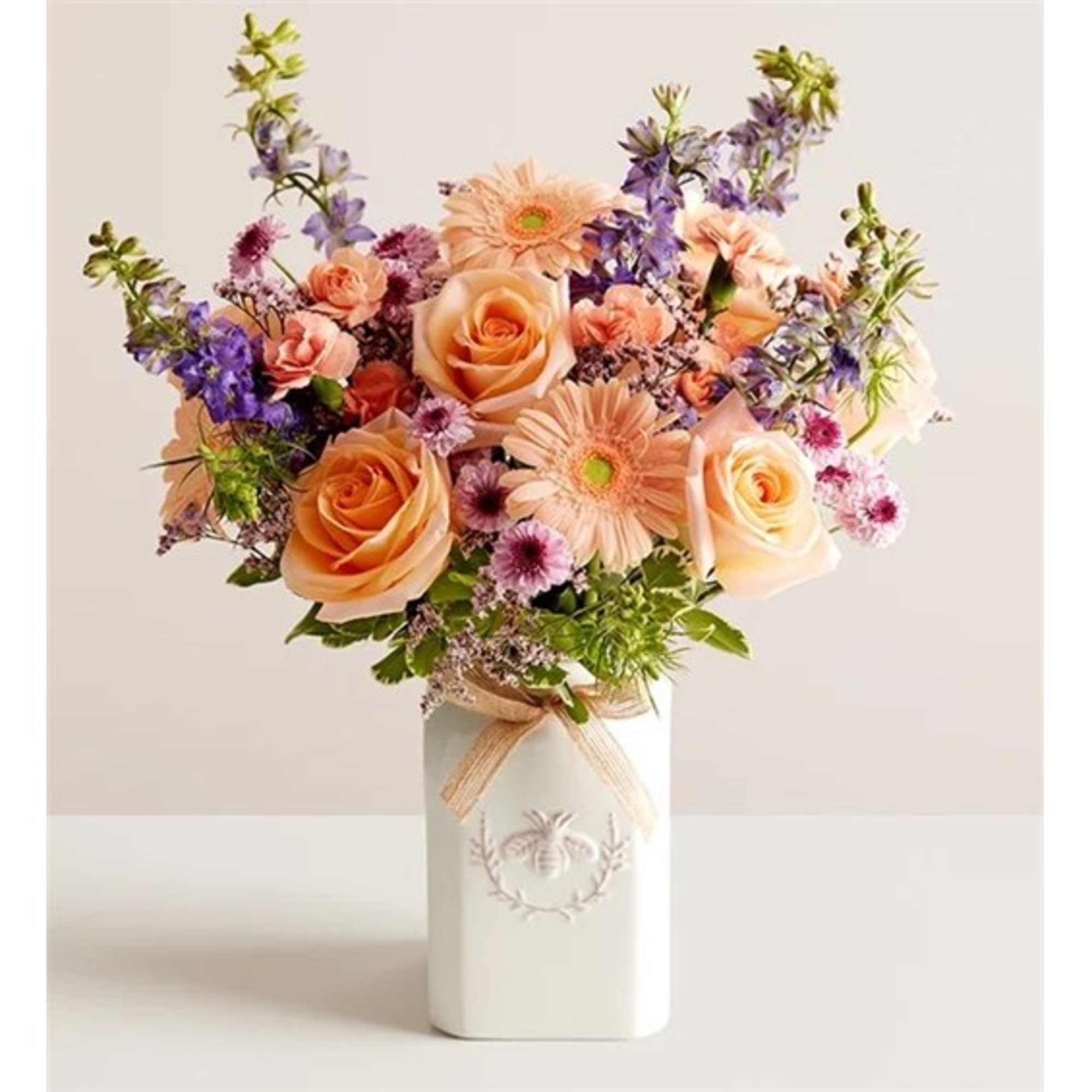 Peach roses and gerbera daisies in a white vase