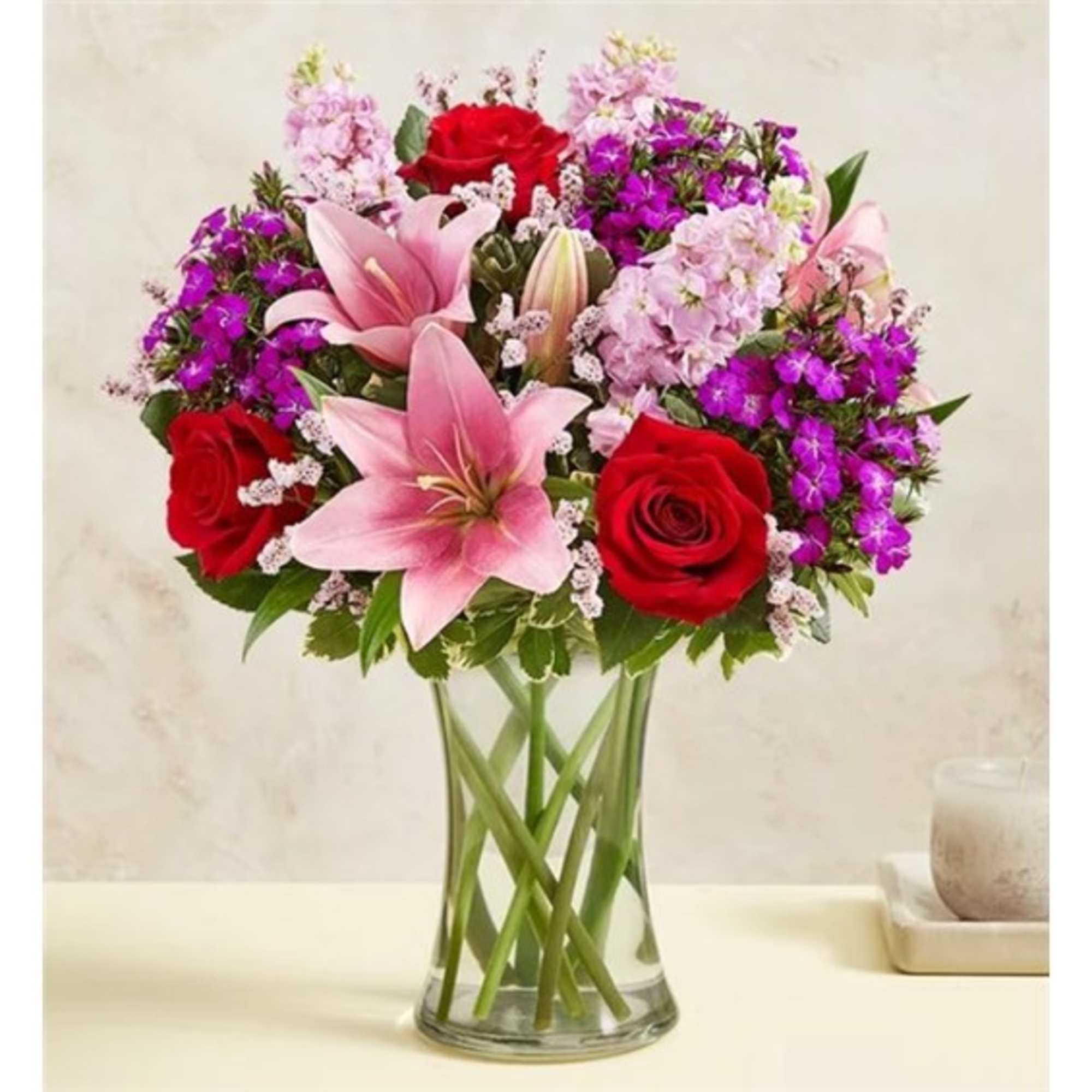 Bouquet of pink lilies and red roses in a clear glass vase