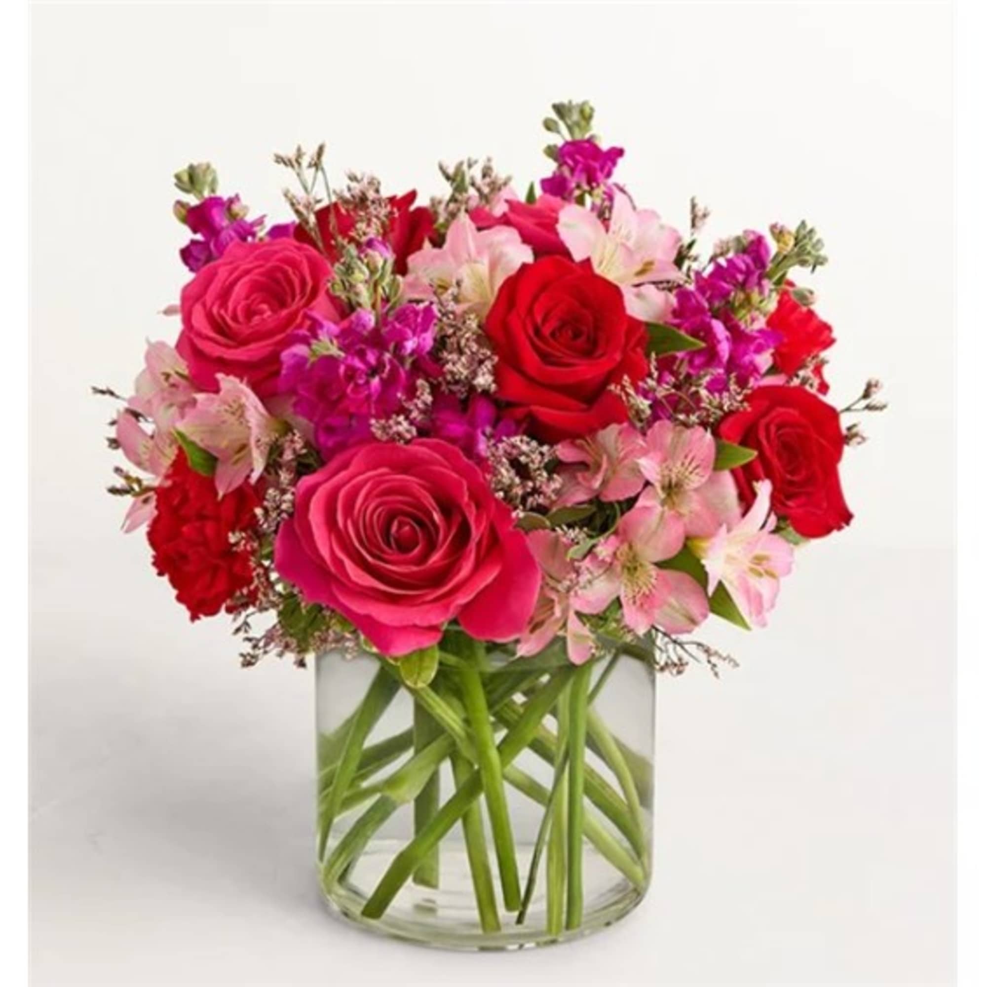 Bouquet of pink and red roses with pale pink flowers in a clear glass vase