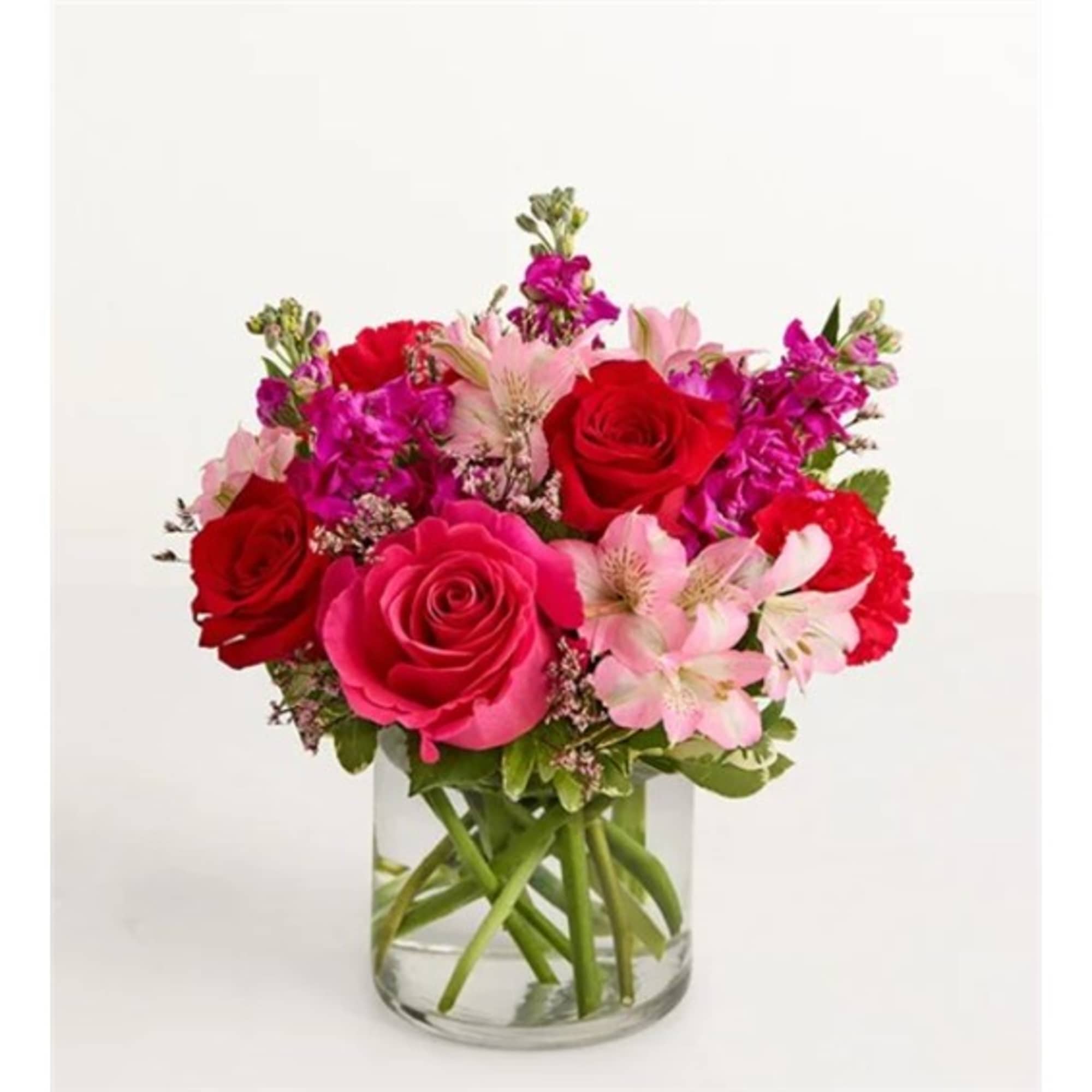 Bouquet of red and pink roses with pale pink flowers in a clear glass vase