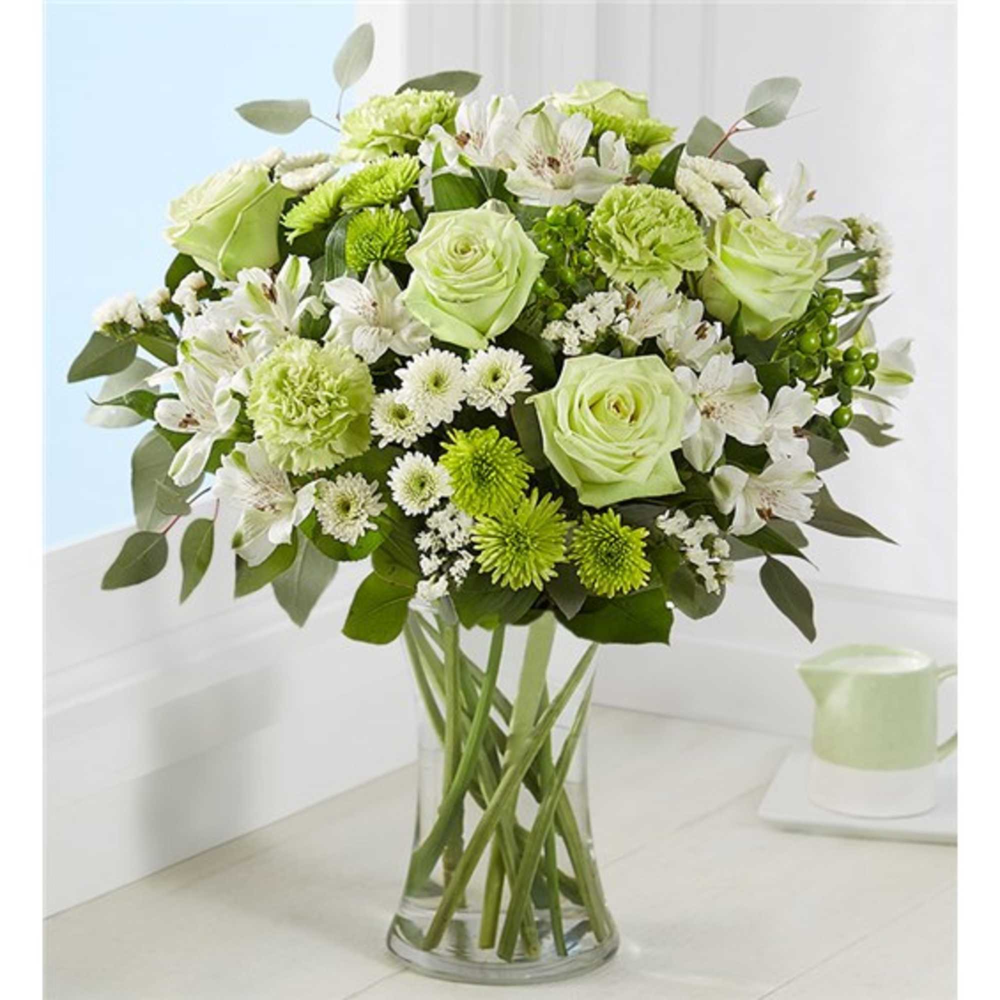 Green and white mixed flower bouquet in a clear glass vase