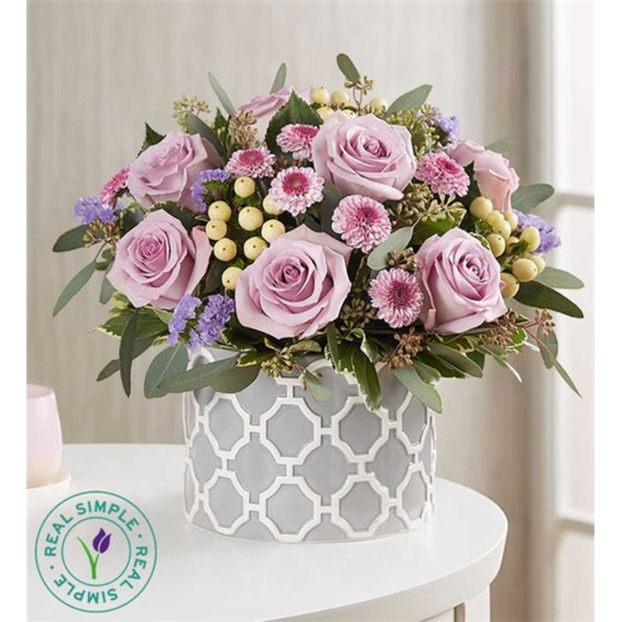 Lavender roses and small pink flowers in a patterned white vase