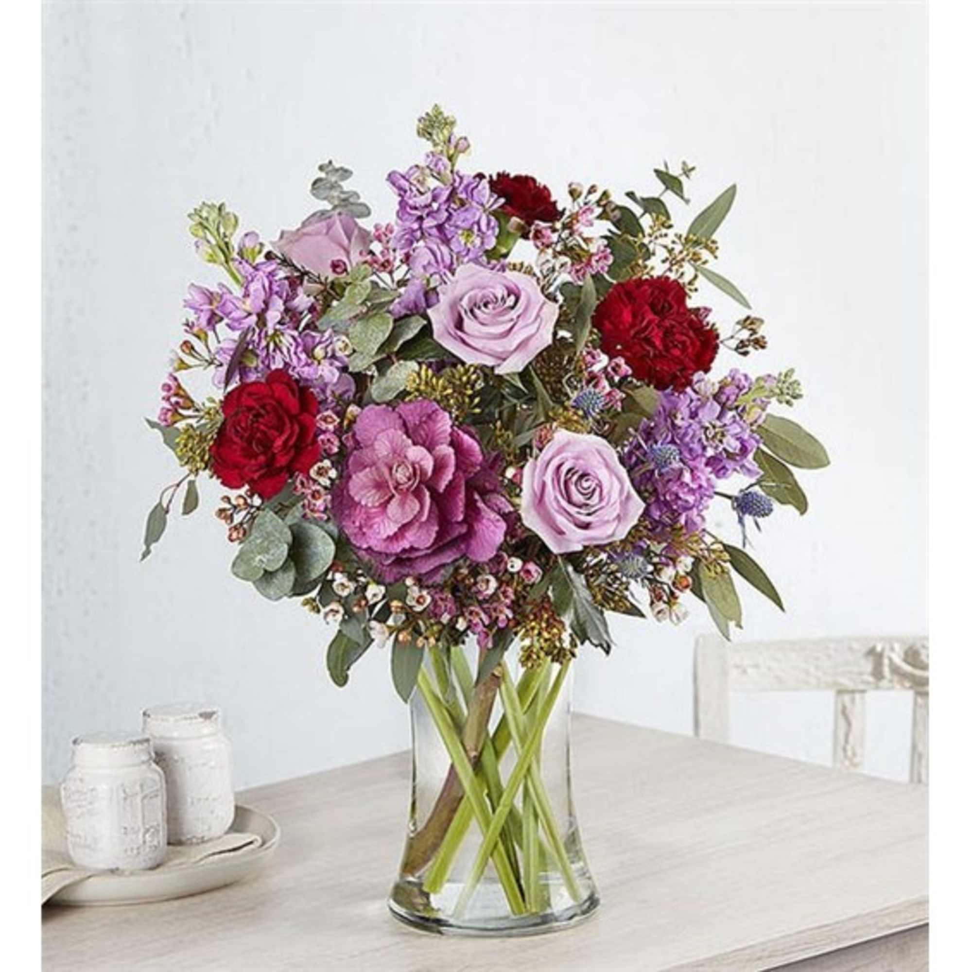 Mixed bouquet of roses and purple flowers in a clear glass vase