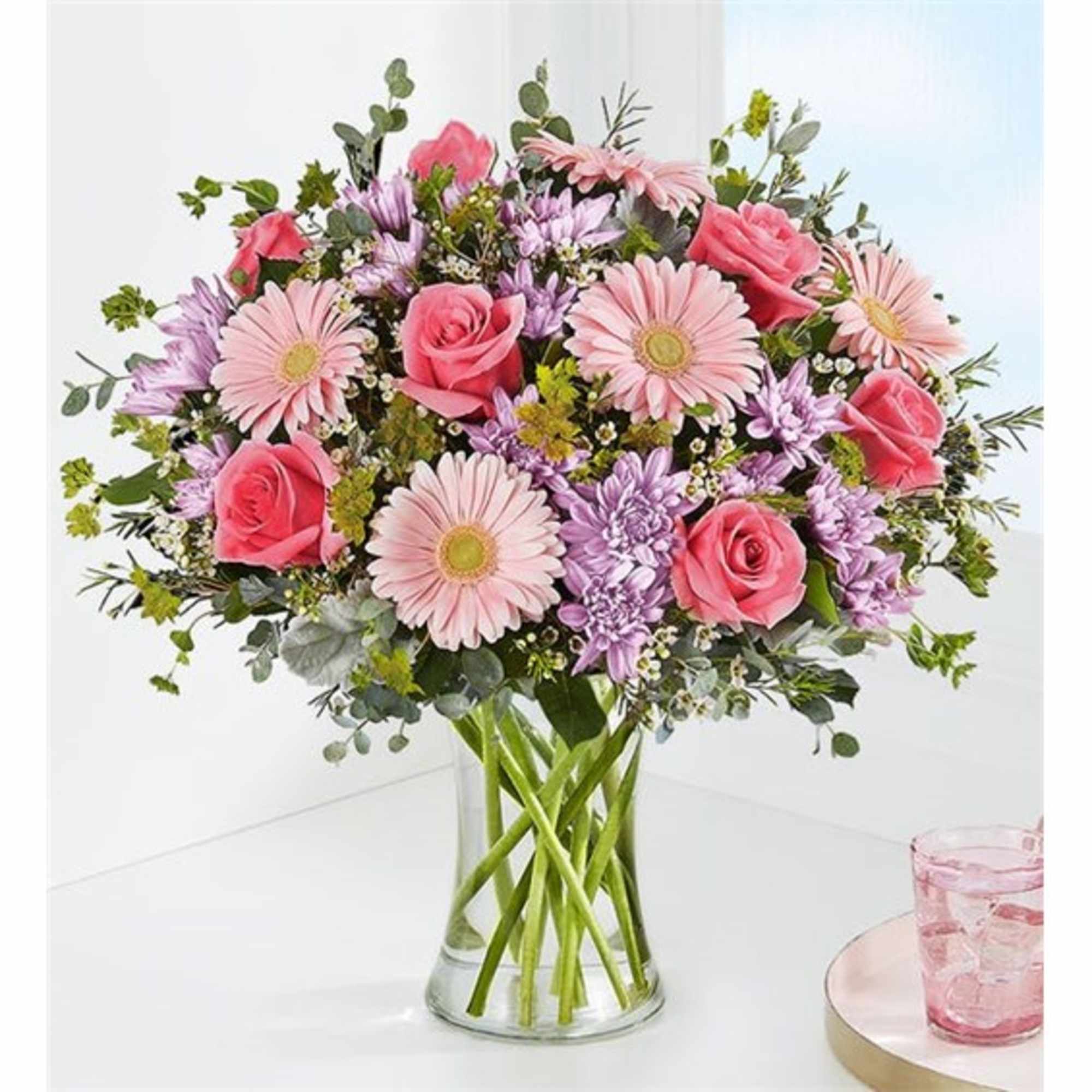 Pink roses and daisies in a clear glass vase