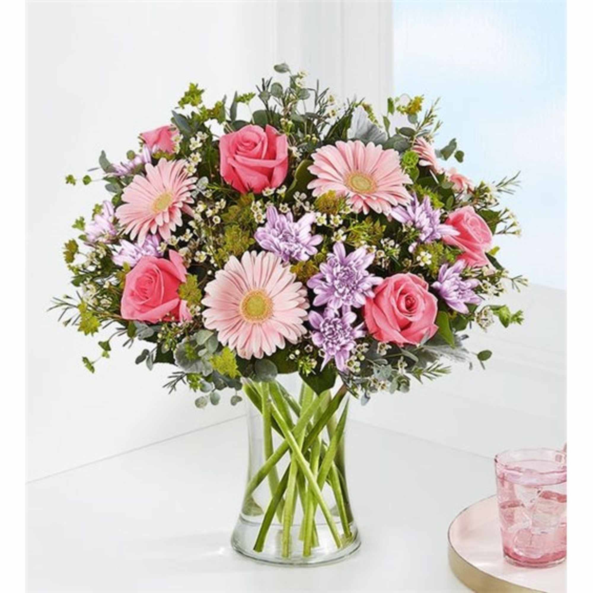 Pink roses and gerbera daisies in a clear glass vase