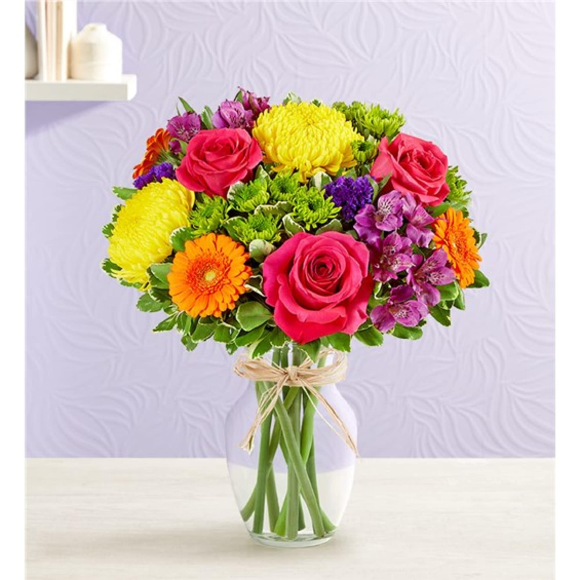 Bouquet of pink roses, yellow chrysanthemums, and orange gerberas in a glass vase