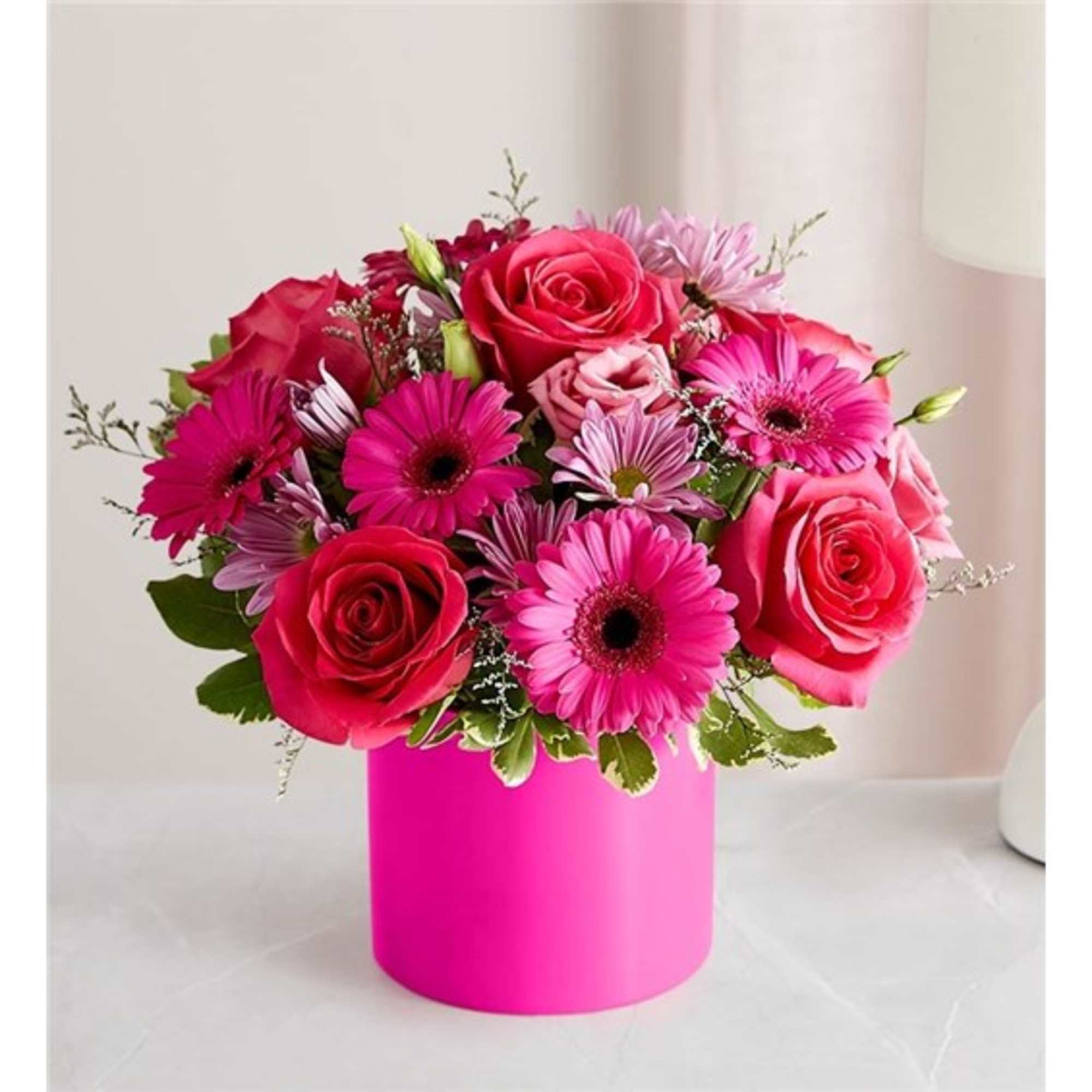 Pink and red rose bouquet in a bright pink cylindrical vase
