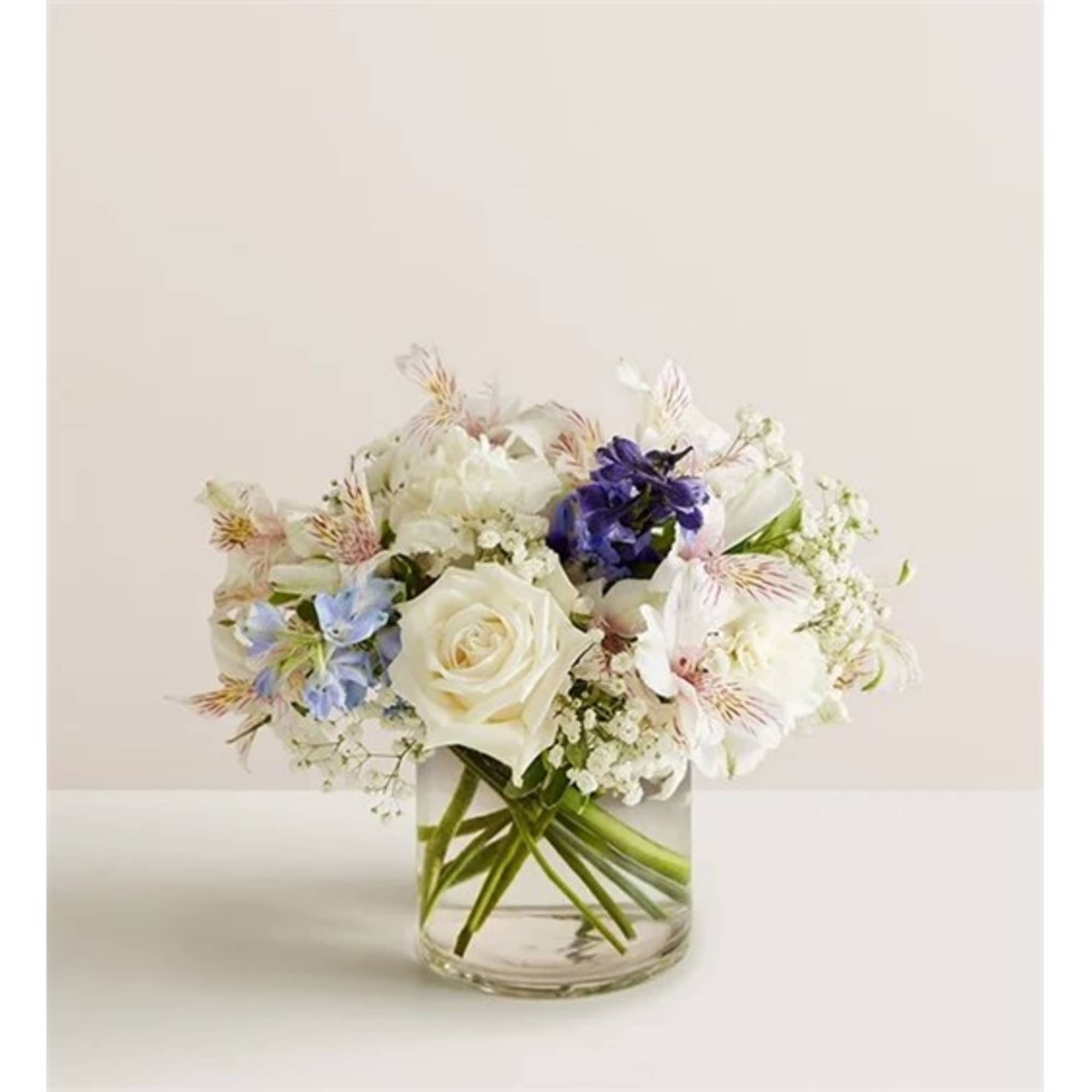 White rose and mixed pastel flowers arranged in a clear glass vase