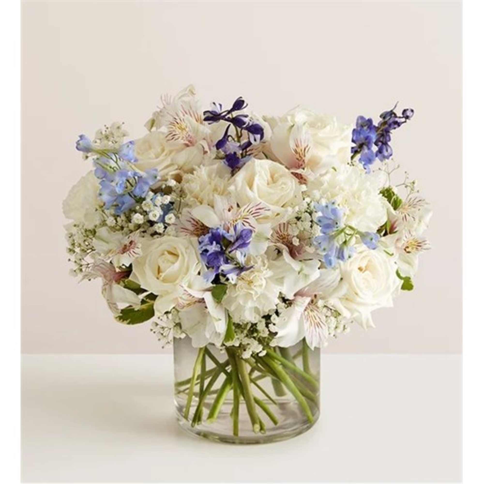 White and blue mixed bouquet in a clear glass vase