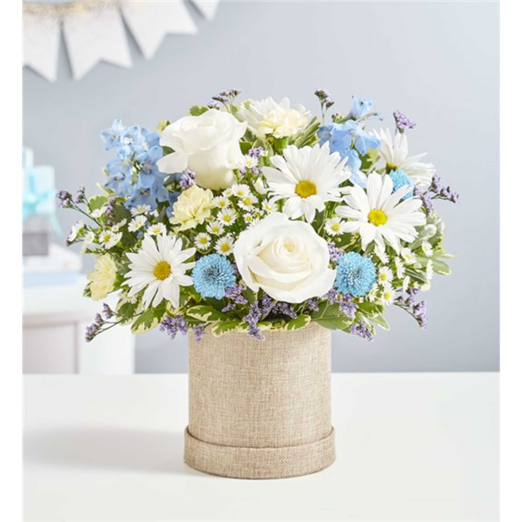 White roses and daisies in a burlap-covered cylinder vase