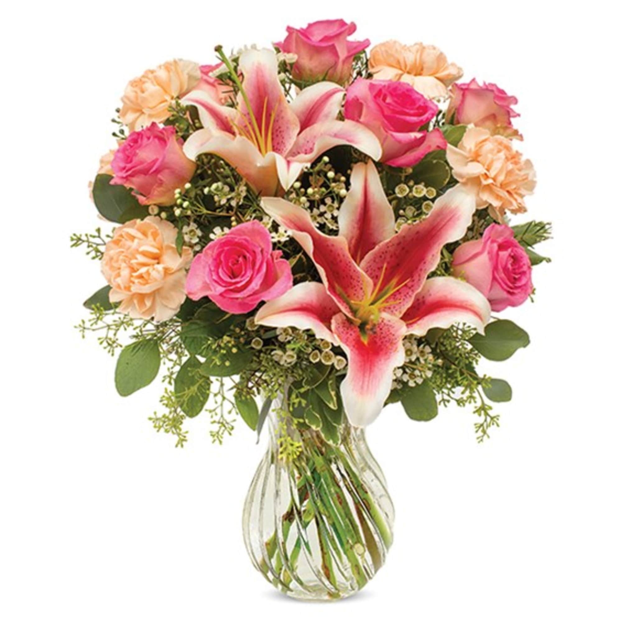 Bouquet of pink roses, lilies, and peach carnations in a clear glass vase