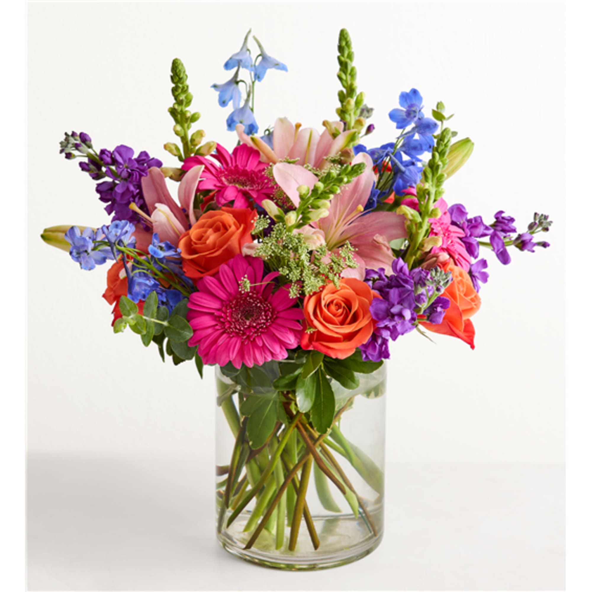 Mixed bouquet of pink, orange, and purple flowers in a clear glass vase