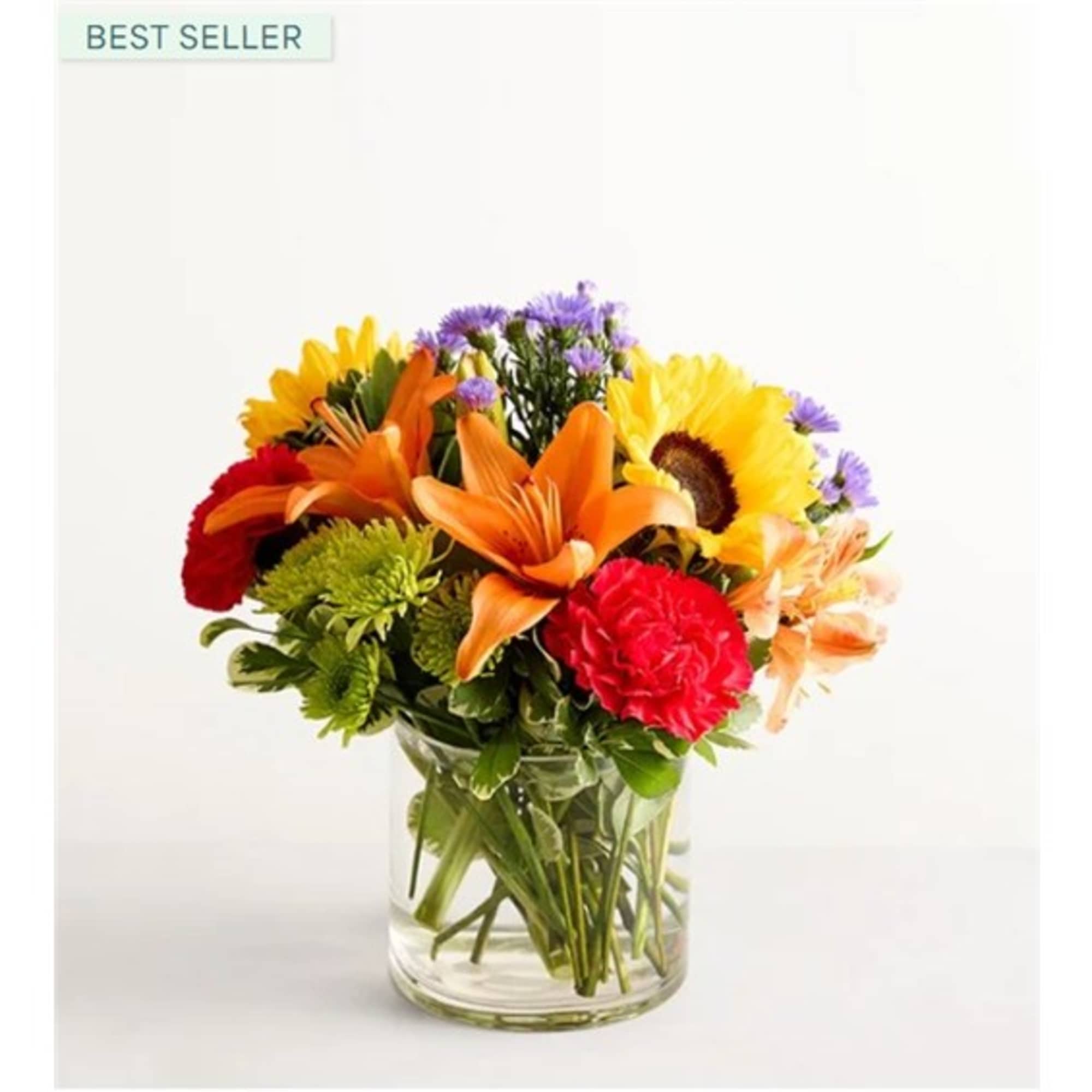 Mixed bouquet of orange lilies, sunflowers, and red carnations in a glass vase