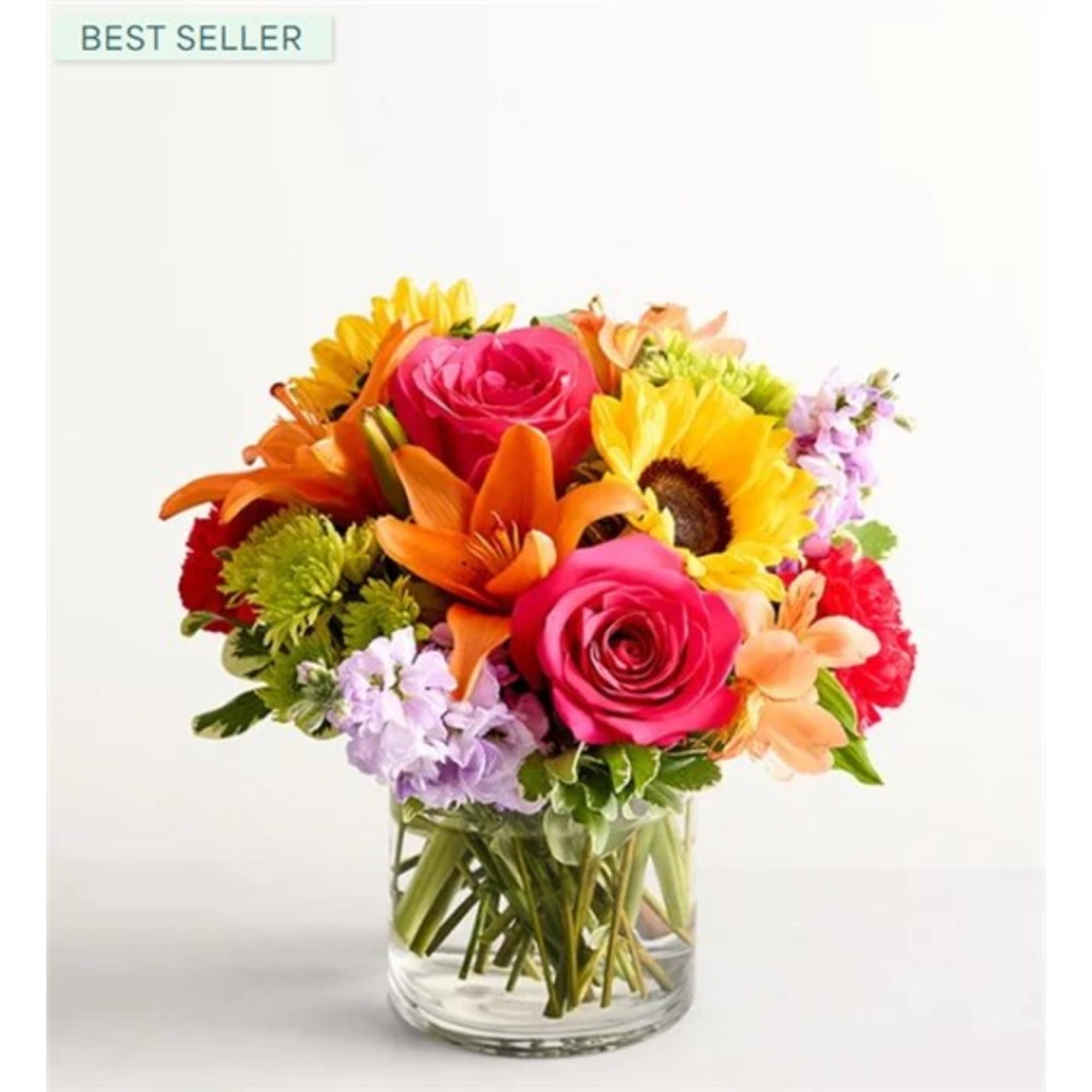 Colorful bouquet of roses, sunflowers, lilies, and mixed blooms in a glass vase