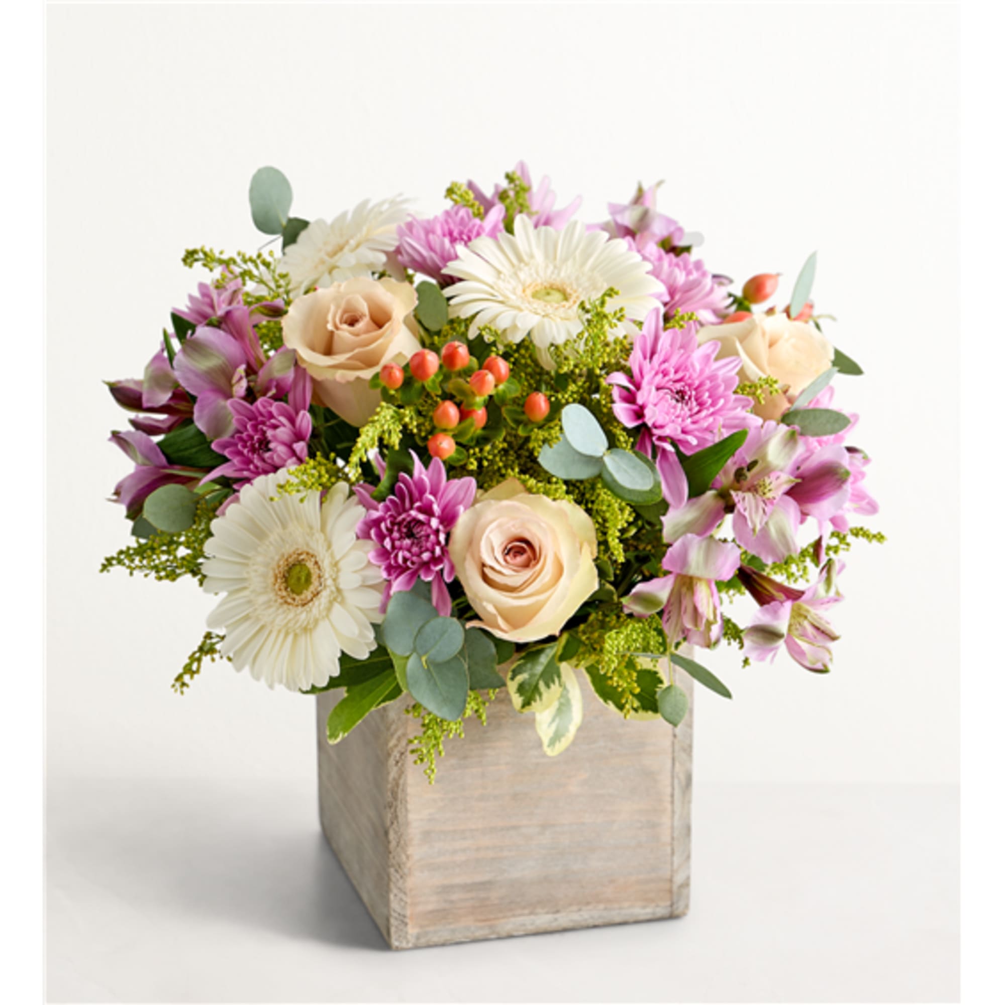 Pink and cream flowers arranged in a wooden cube vase