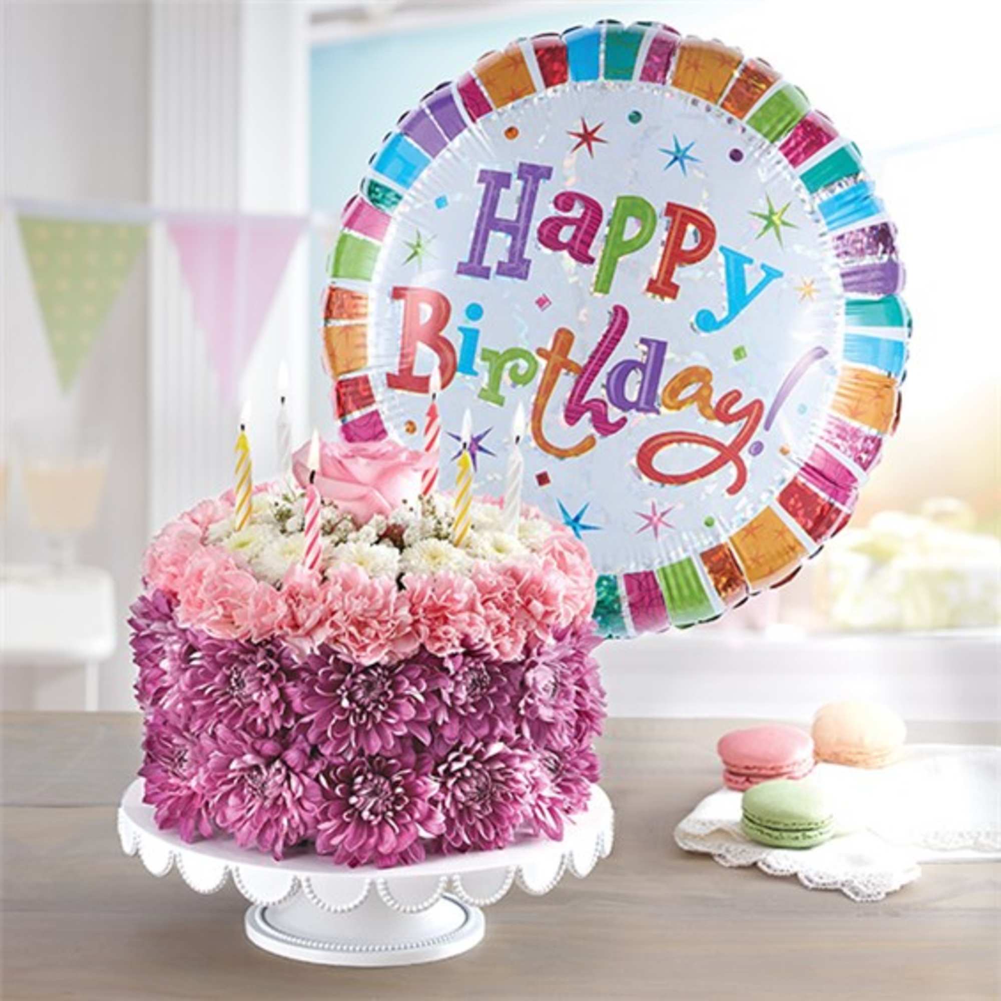 Pink and purple flower cake with birthday candles and a Happy Birthday balloon