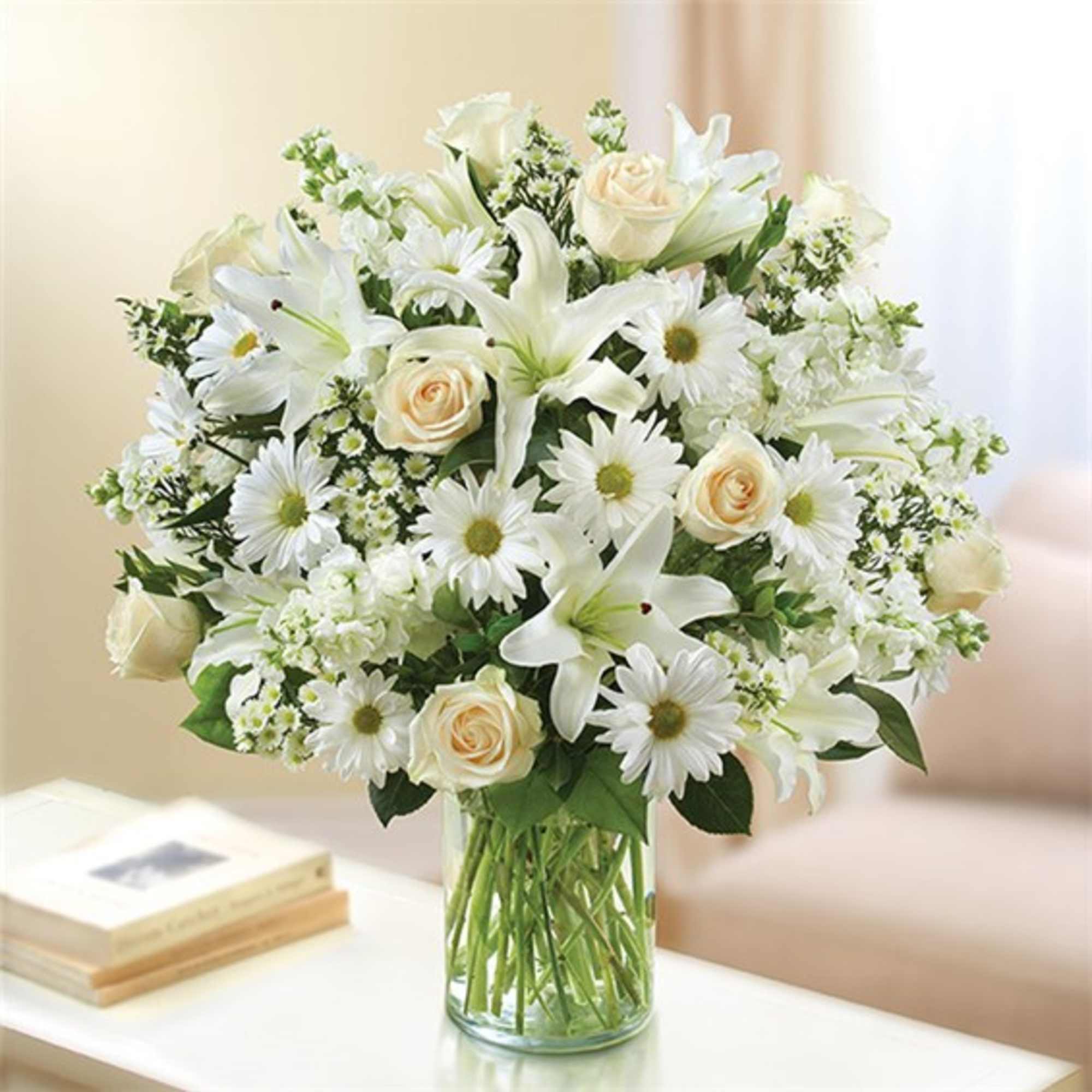 White flowers and cream roses arranged in a clear glass vase