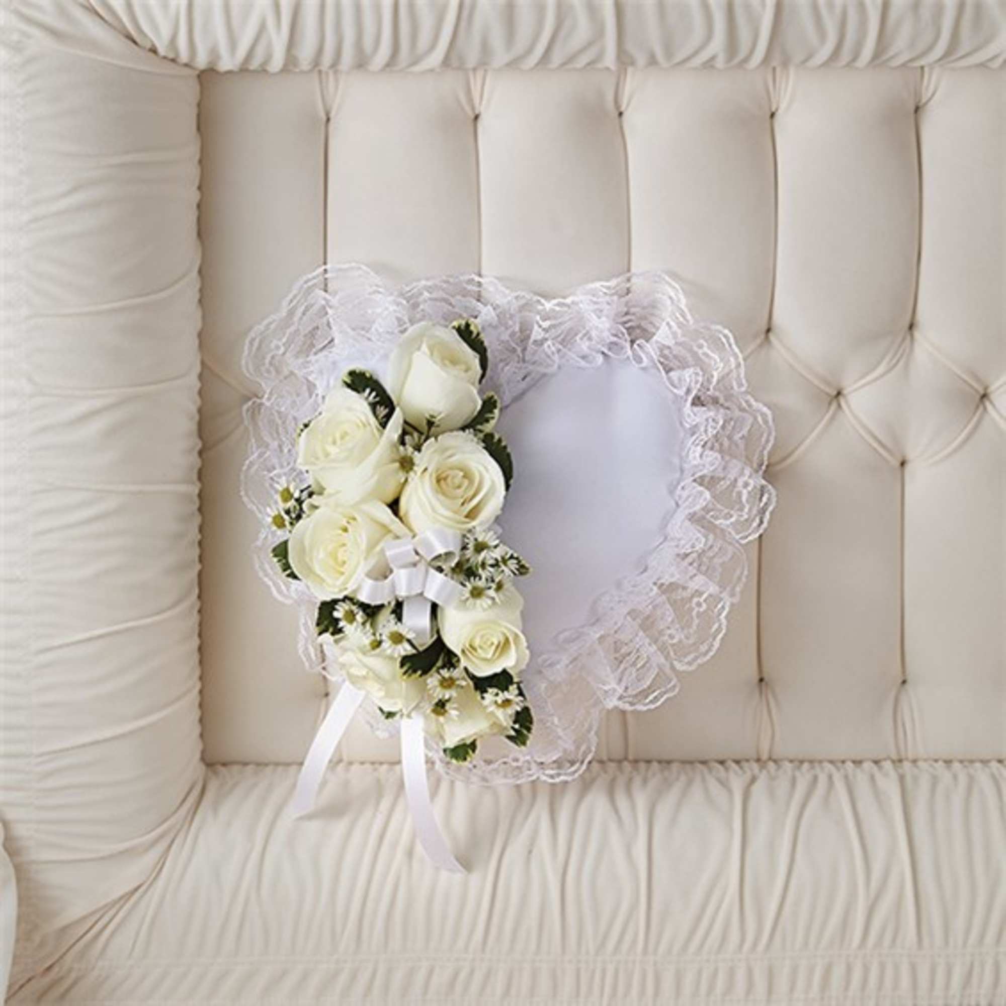 White rose bouquet with lace trim and ribbon on a cream tufted chair