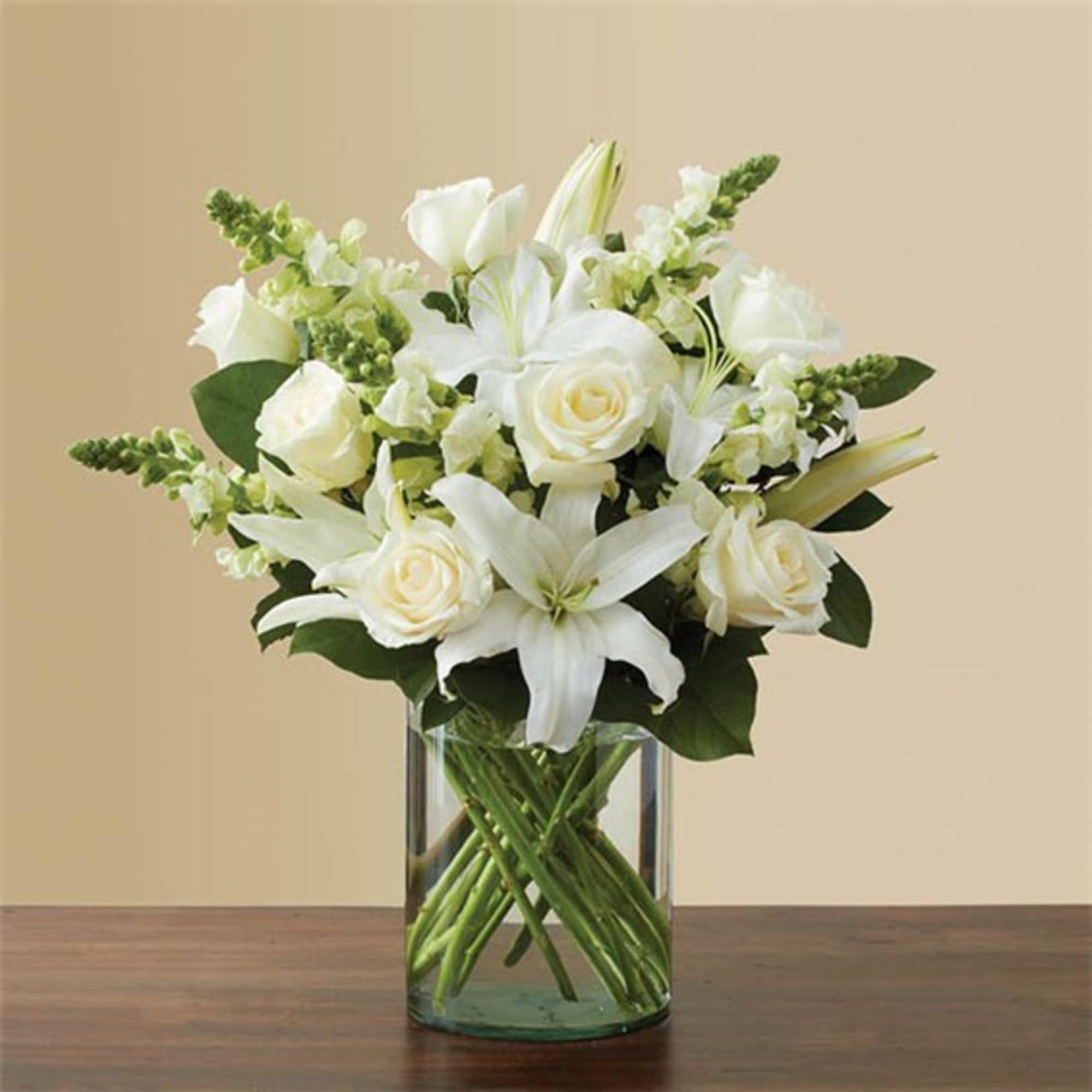 White roses and lilies arranged in a clear glass vase