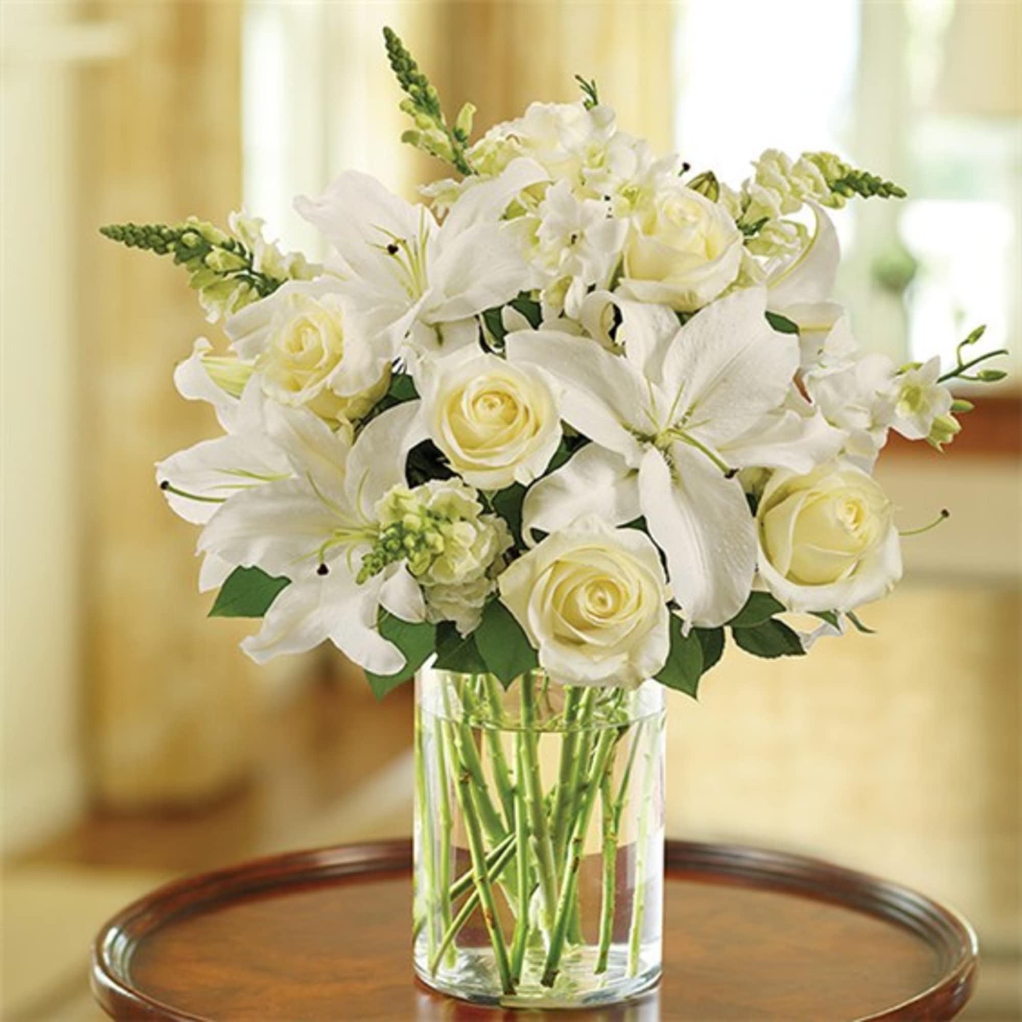 White roses and lilies arranged in a clear glass vase