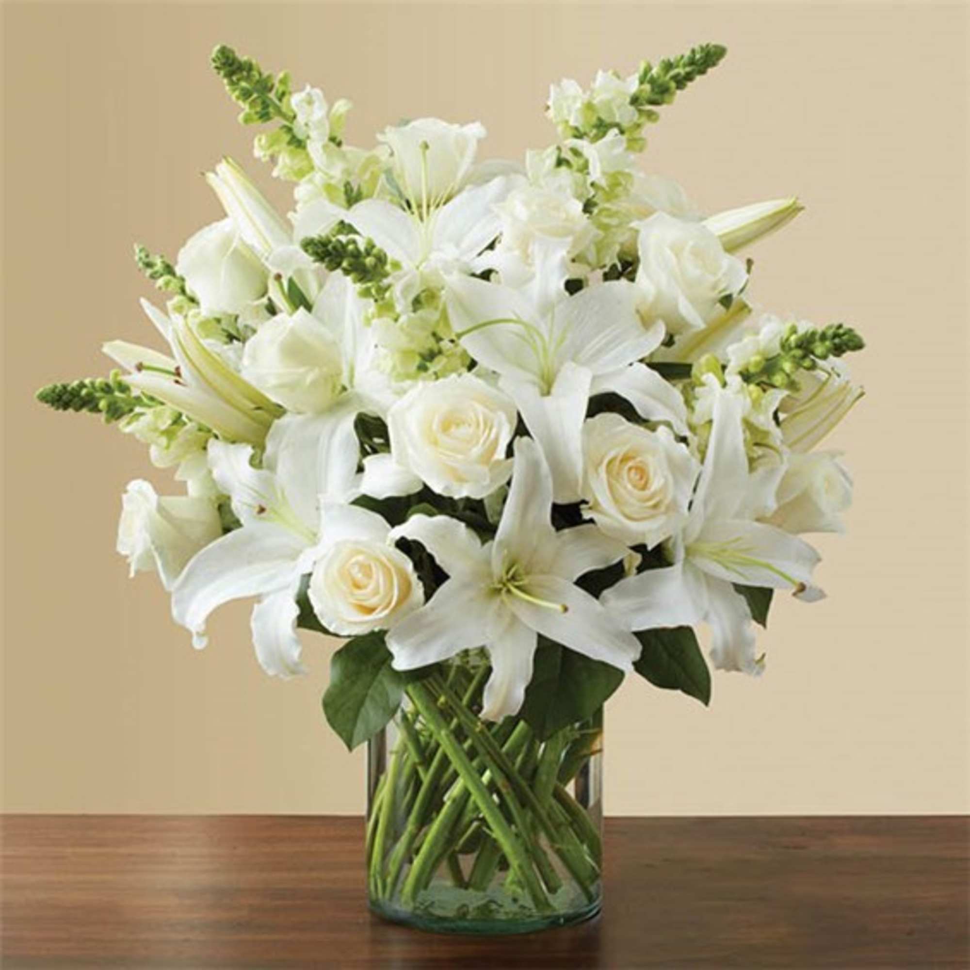 White lilies and roses arranged in a clear glass vase