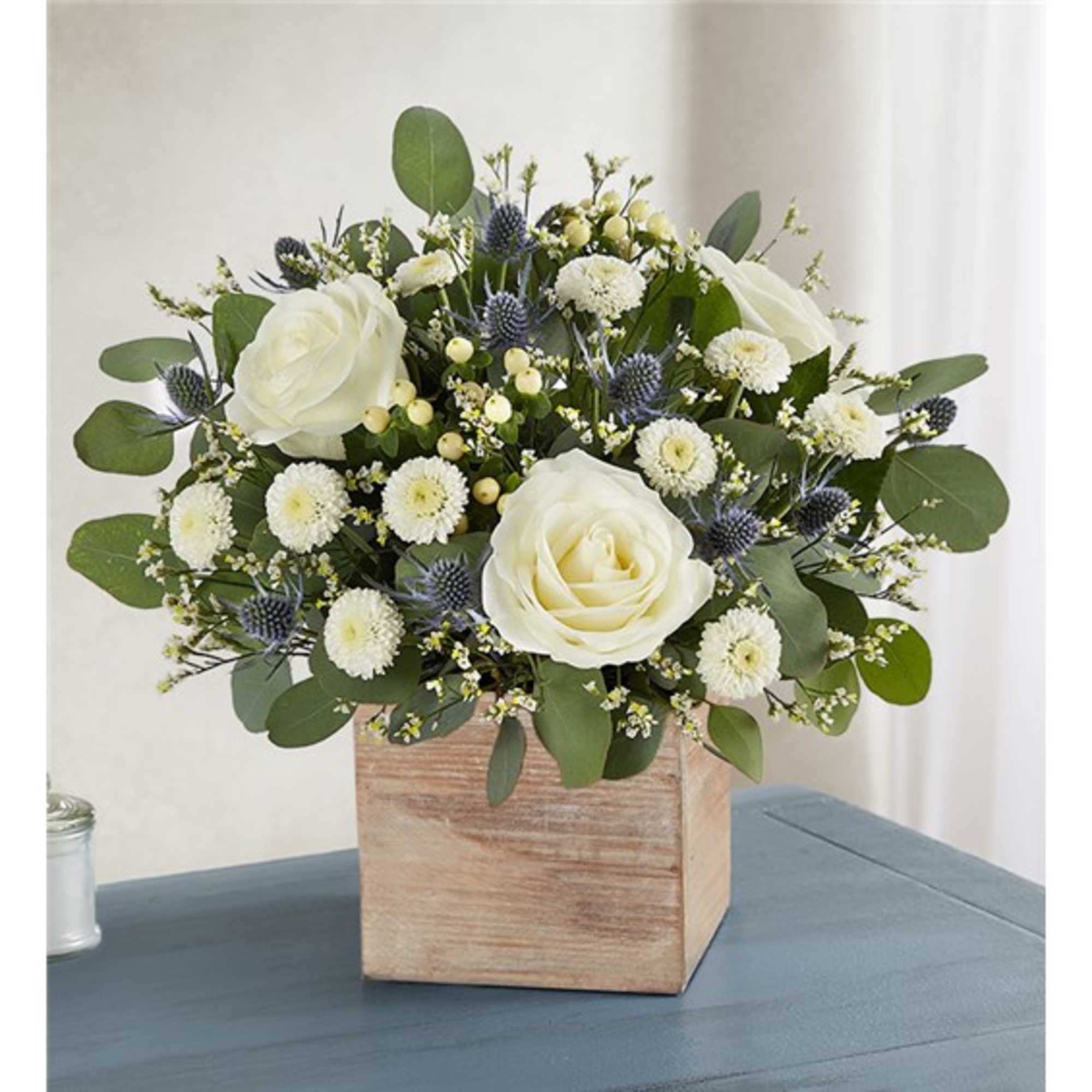 White roses and small white blooms in a wooden box vase