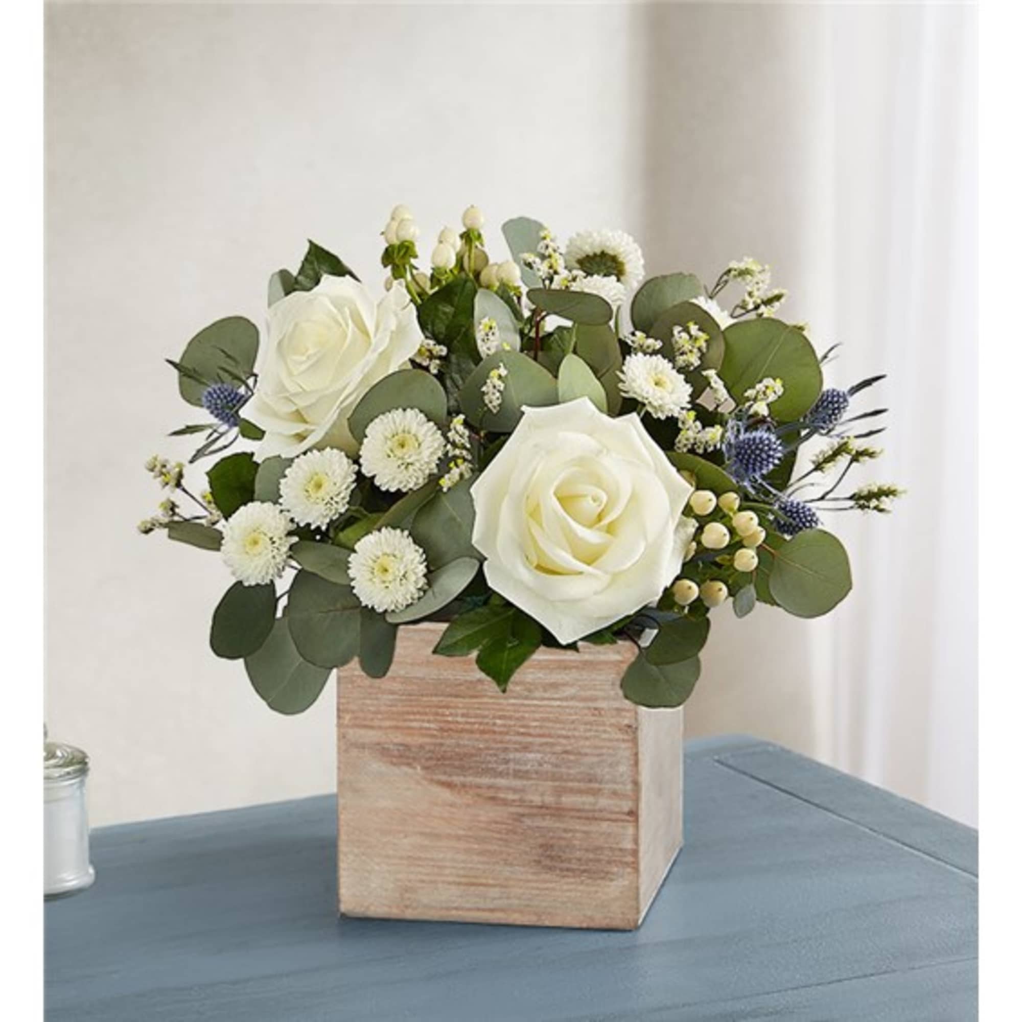 White roses and small white blooms in a wooden box vase