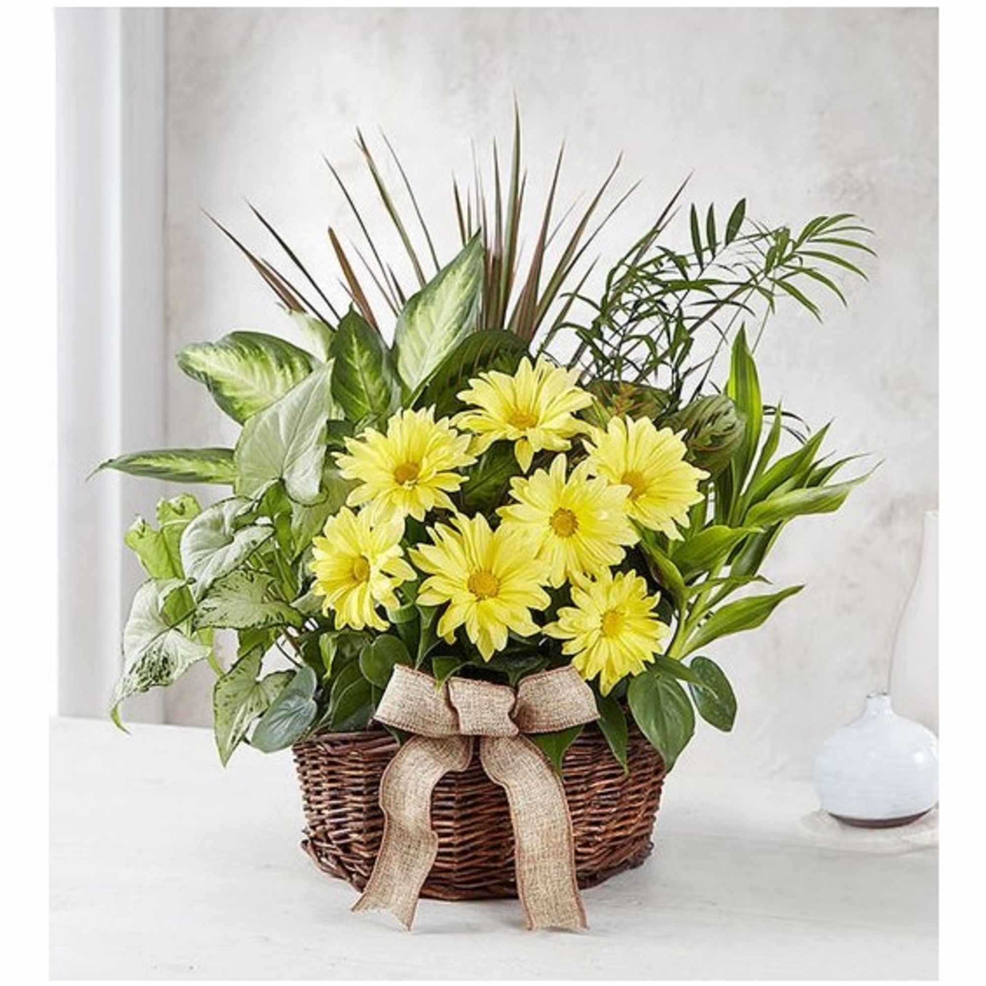 Yellow daisies in a wicker basket with a burlap bow