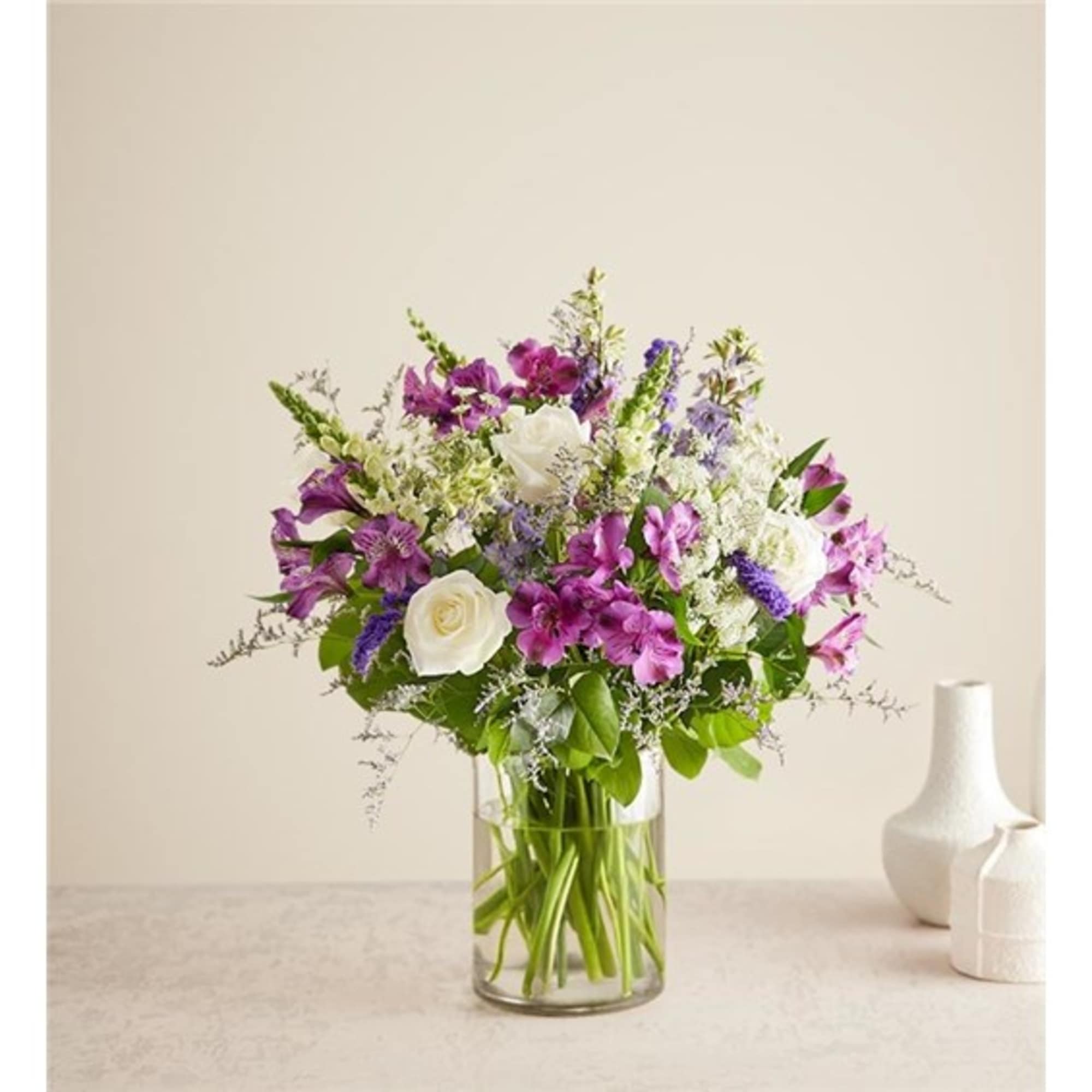 Mixed bouquet of purple and white flowers in a clear glass vase