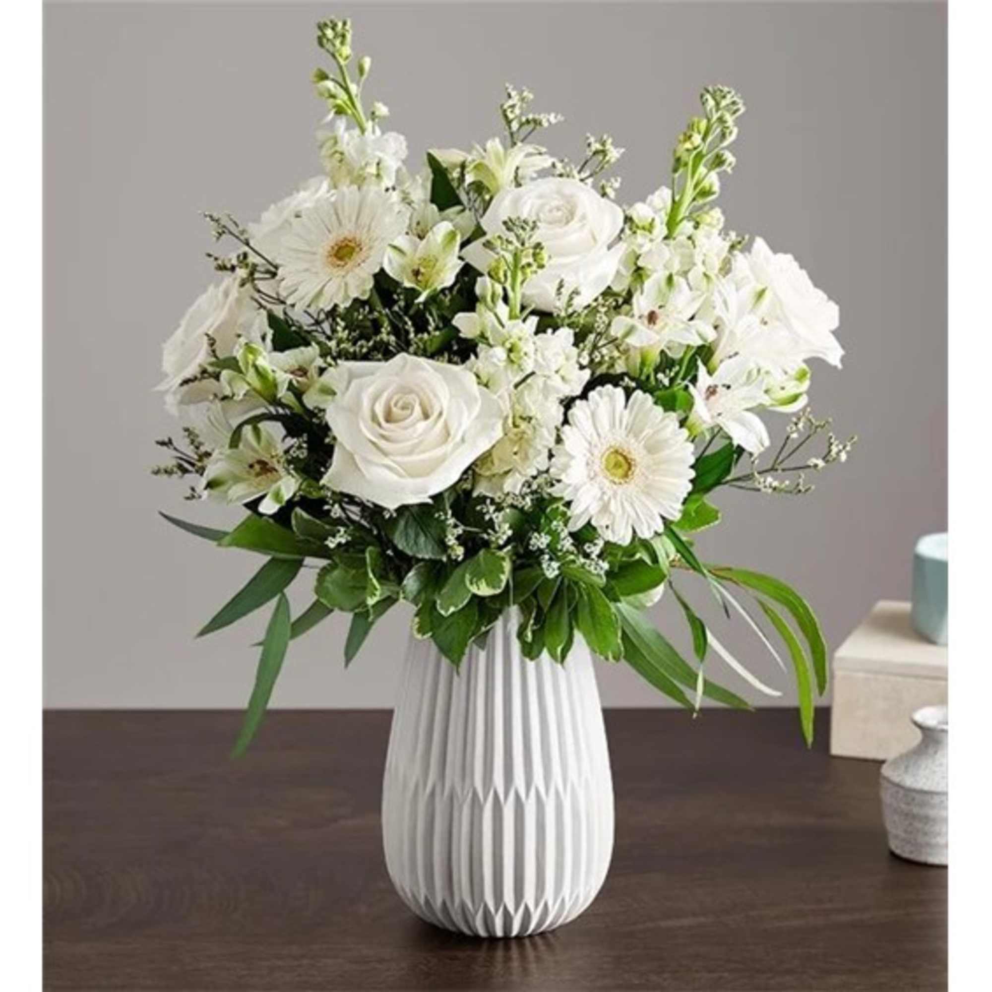 White floral arrangement in a ribbed vase with roses and daisy-like blooms