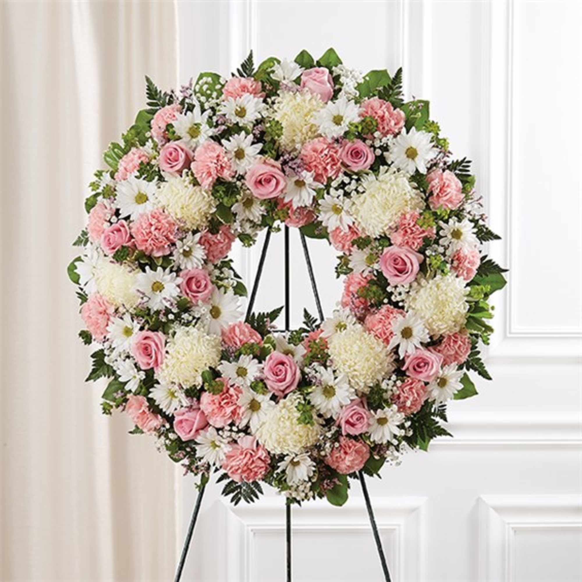 Pink and white floral wreath on a black stand