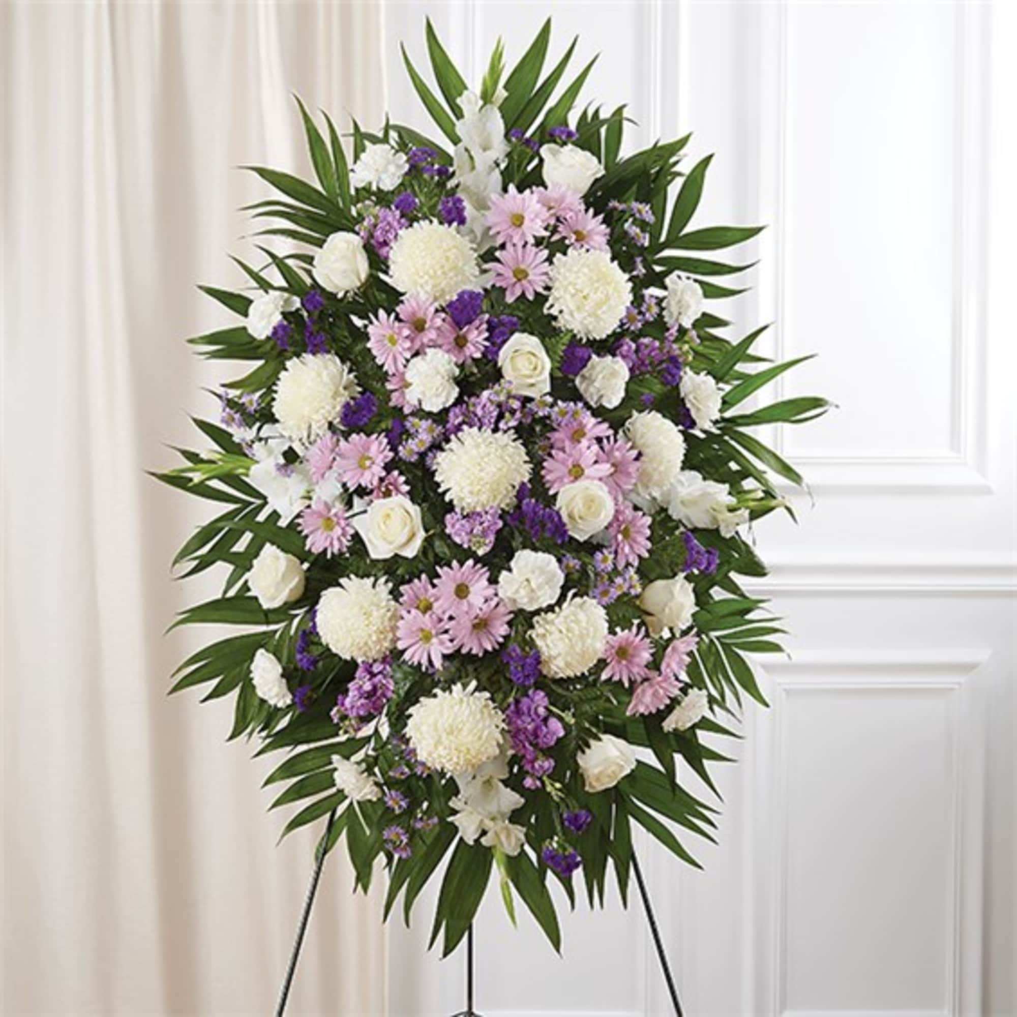 Standing floral spray with white, pink, and purple flowers on a tripod easel