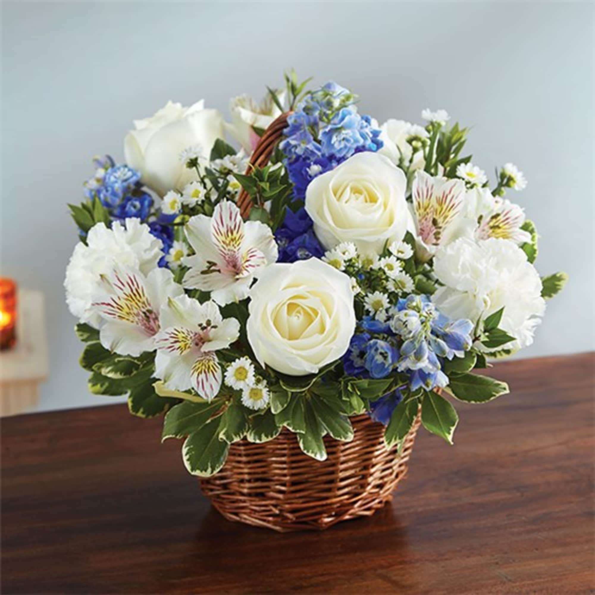 Basket arrangement of white roses, blue flowers, and white alstroemeria