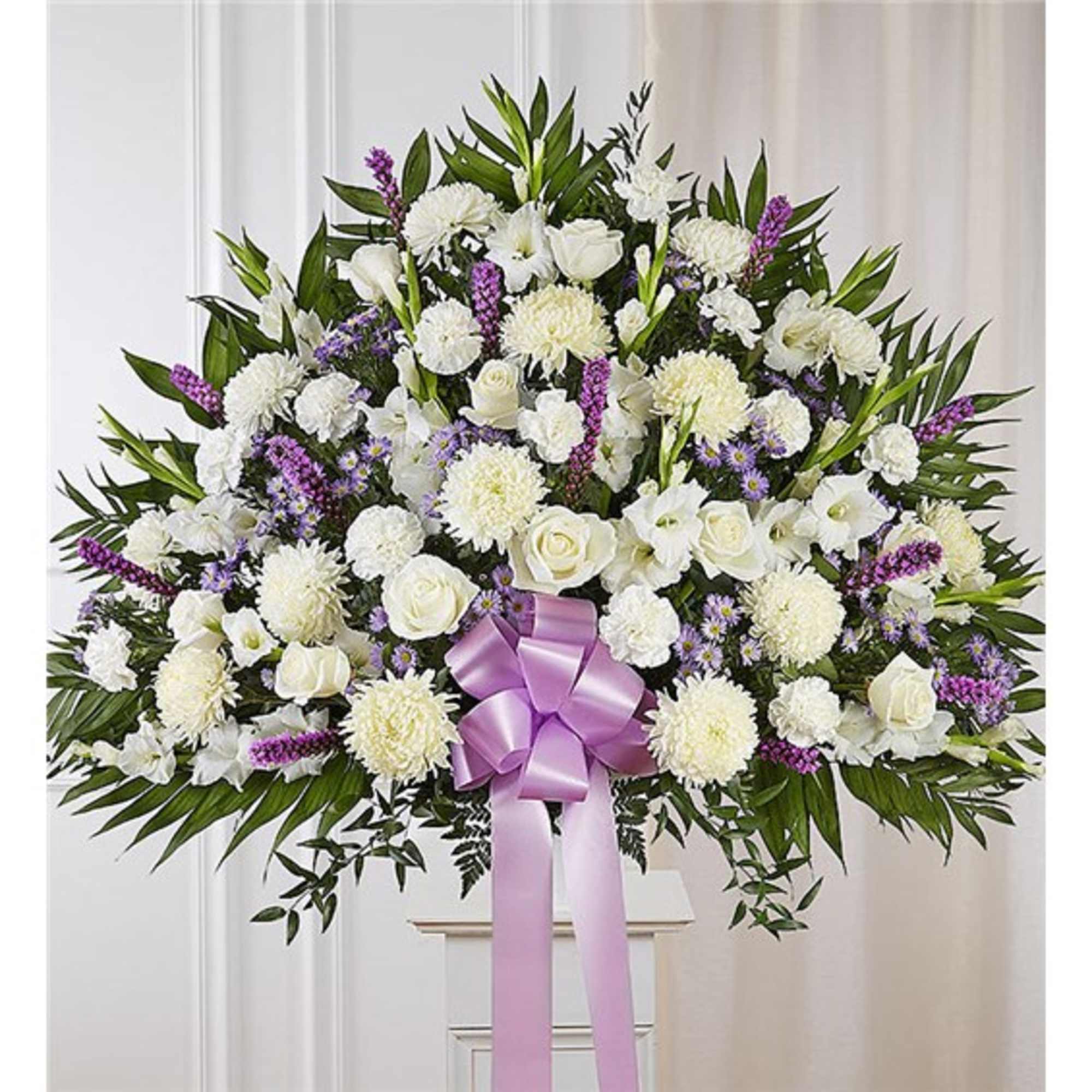 Large white floral spray with a lavender ribbon on a stand