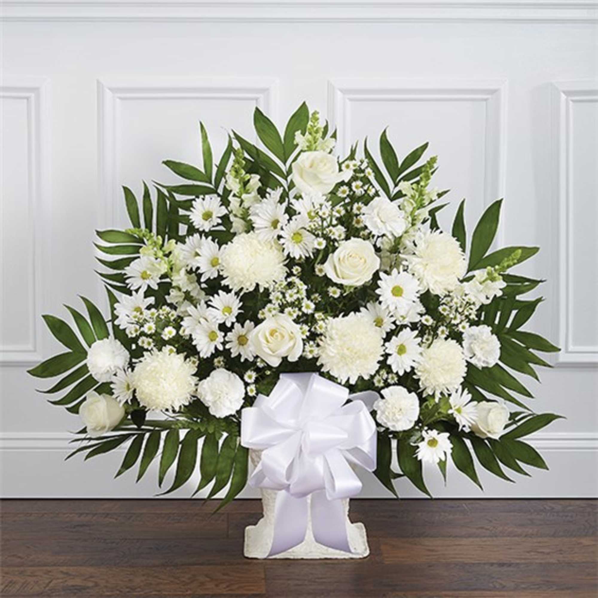 White floral arrangement with daisies and roses in a pedestal vase