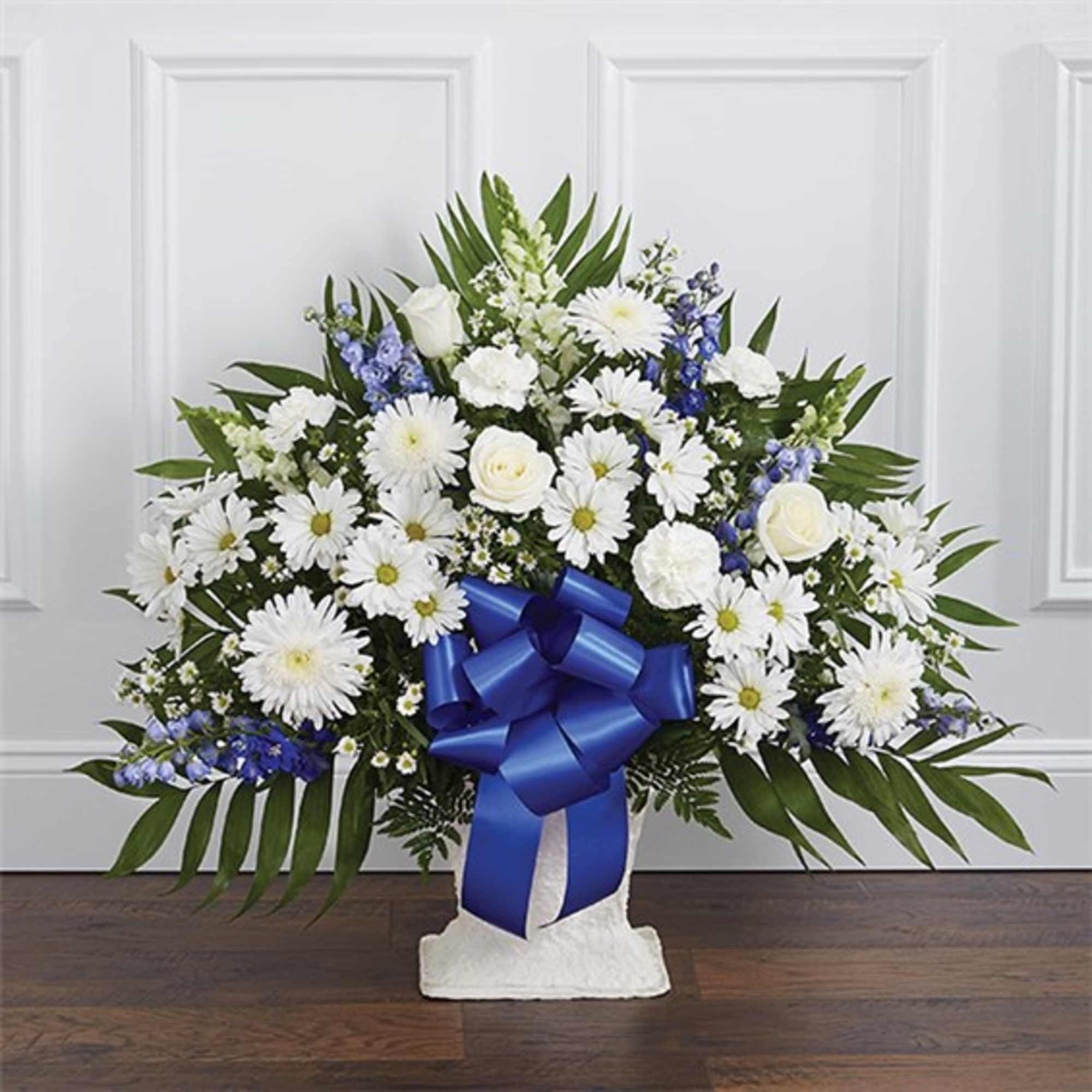 White daisies and roses in a white vase with a blue ribbon