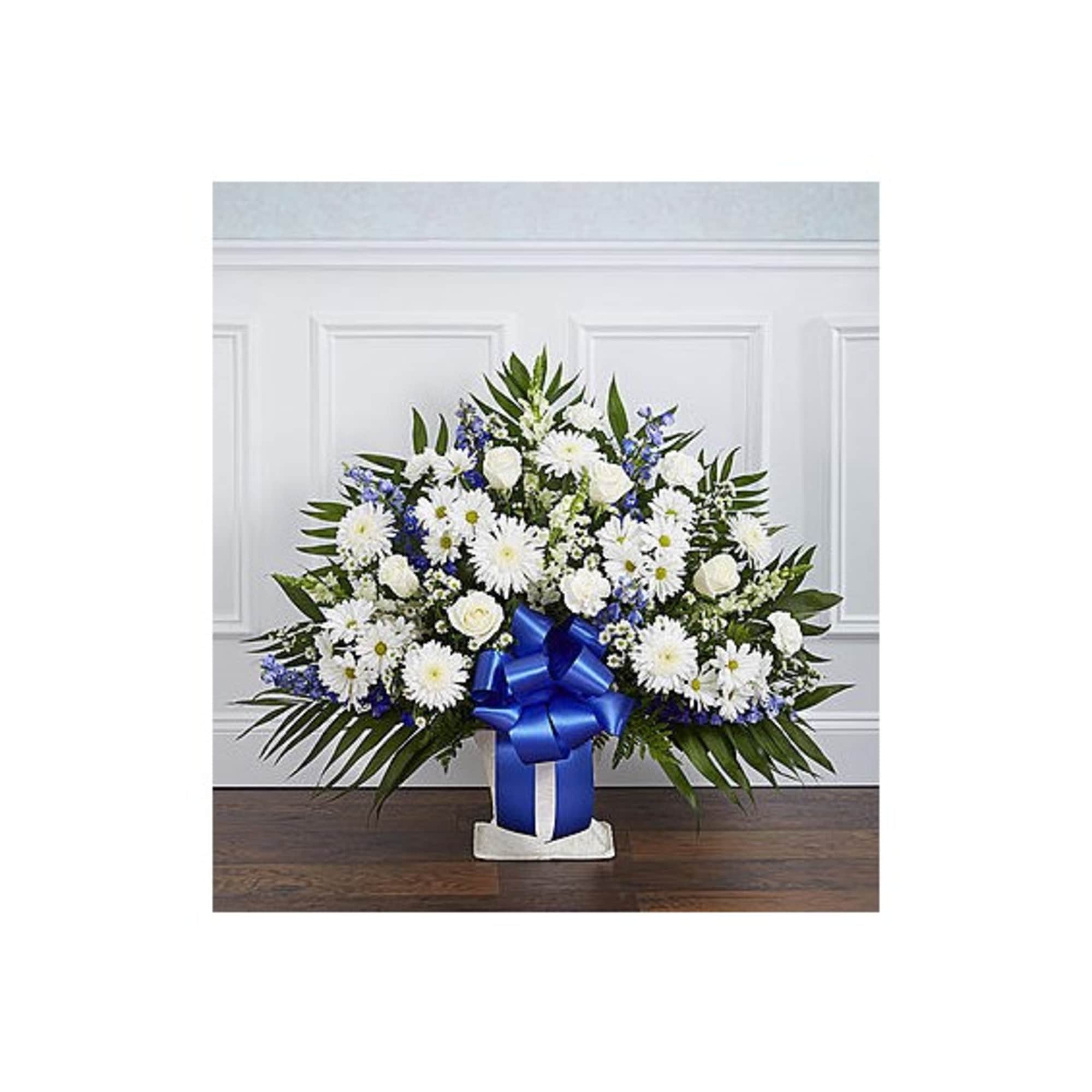 White and blue floral arrangement in a vase with a blue ribbon