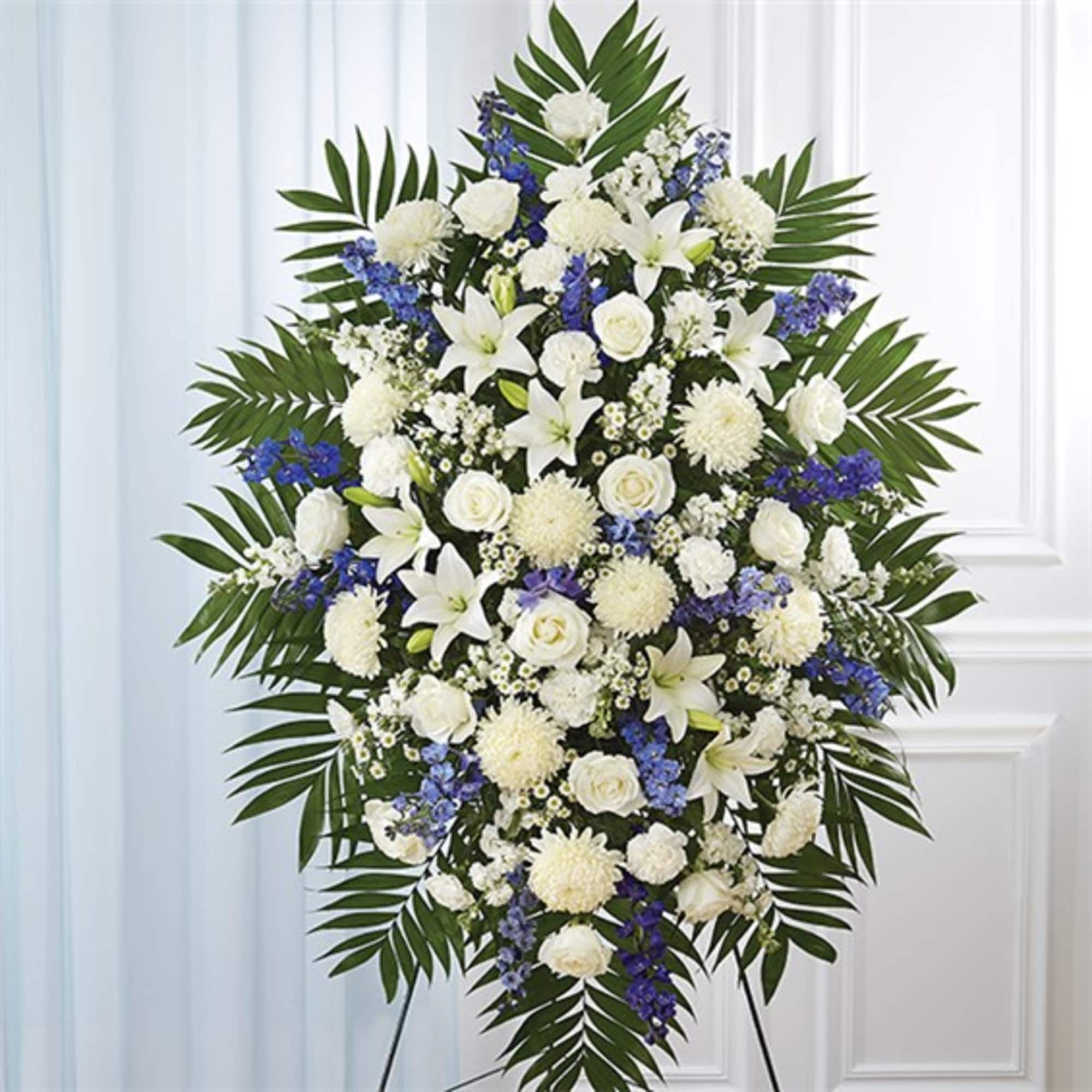Standing floral spray of white and blue flowers with palm leaves